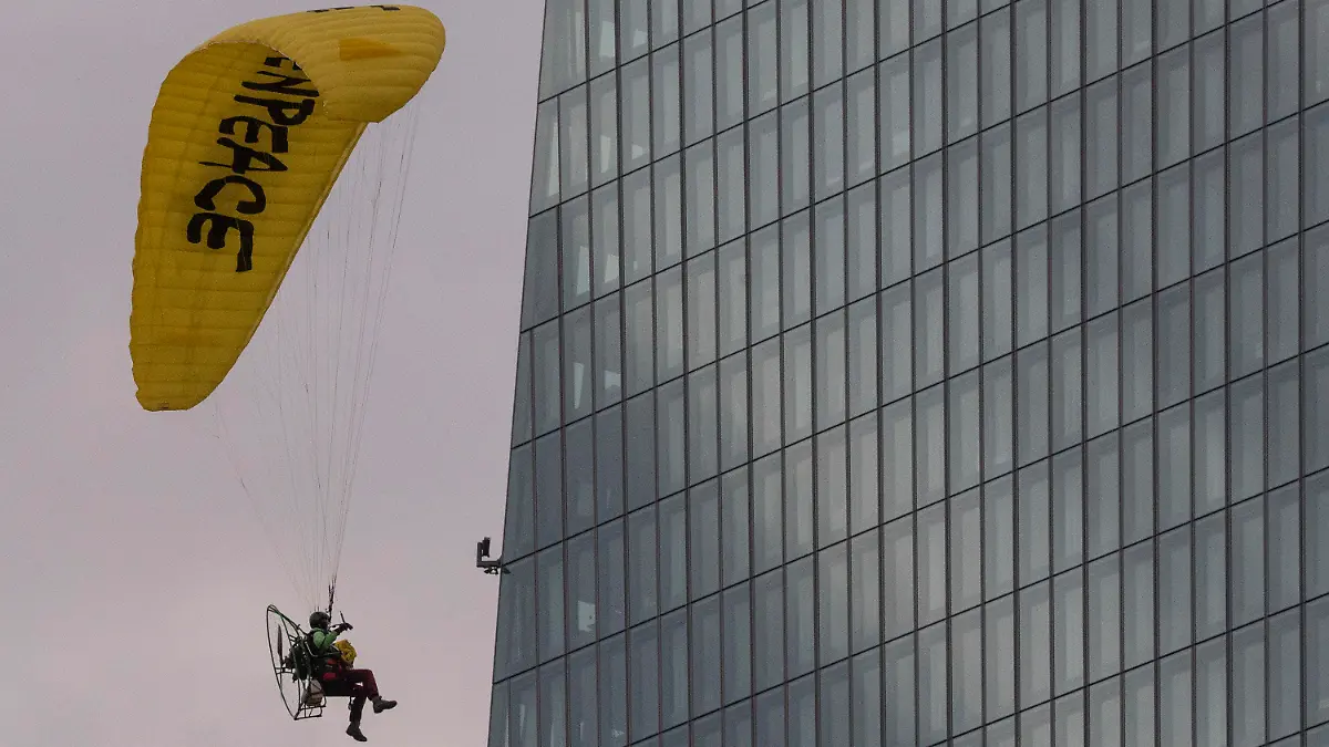 10.03.2021, Hessen, Frankfurt/Main: Mit einem Gleitschirm landet ein Greenpeace-Aktivist auf dem Dach der Europäischen Zentralbank (EZB). Dort entrollten die Aktivisten einen Tag vor der EZB-Ratssitzung ein Transparent gegen die Klimapolitik der EZB. Foto: Boris Roessler/dpa +++ dpa-Bildfunk +++