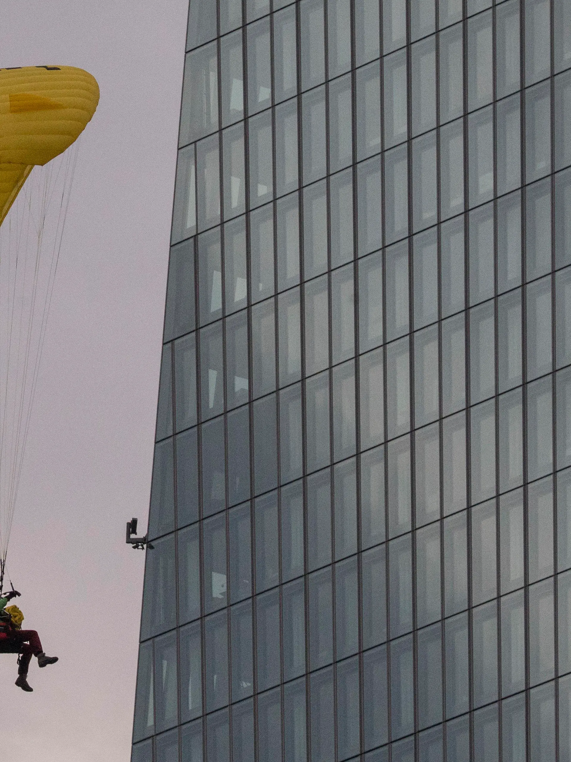 10.03.2021, Hessen, Frankfurt/Main: Mit einem Gleitschirm landet ein Greenpeace-Aktivist auf dem Dach der Europäischen Zentralbank (EZB). Dort entrollten die Aktivisten einen Tag vor der EZB-Ratssitzung ein Transparent gegen die Klimapolitik der EZB. Foto: Boris Roessler/dpa +++ dpa-Bildfunk +++