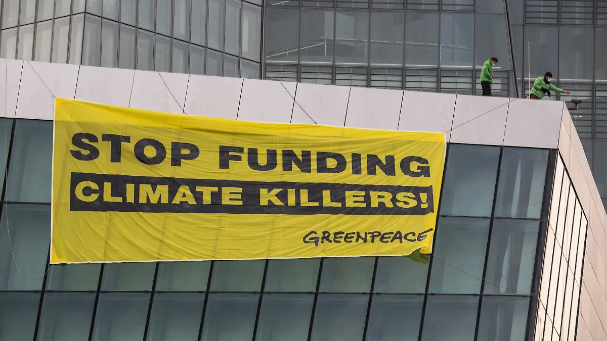 10.03.2021, Hessen, Frankfurt/Main: "Stop funding climate killers" steht auf einem Plakat, das Greenpeace-Aktivisten auf dem Dach der Europäischen Zentralbank (EZB) entrollt haben. Dazu waren zwei Aktivisten mit Gleitschirmen auf dem schwer gesicherten Areal gelandet. Mit der Aktion protestiert Greenpeace am Tag vor der EZB-Ratssitzung gegen die Klimapolitik der EZB. Foto: Boris Roessler/dpa +++ dpa-Bildfunk +++