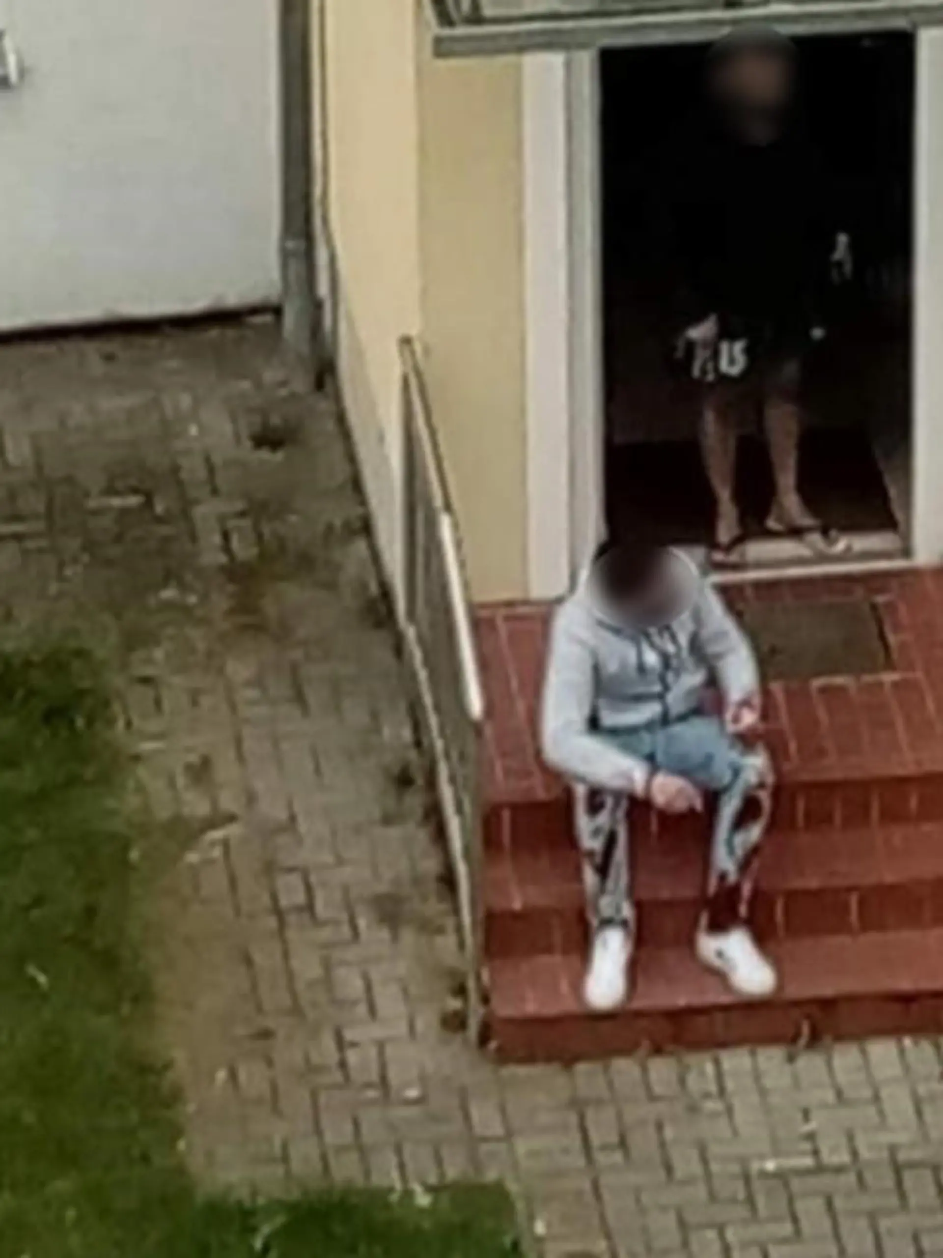 Hier sitzt der mutmaßliche Ex-Freund des Opfers mit blutiger Hose vor dem Hauseingang.