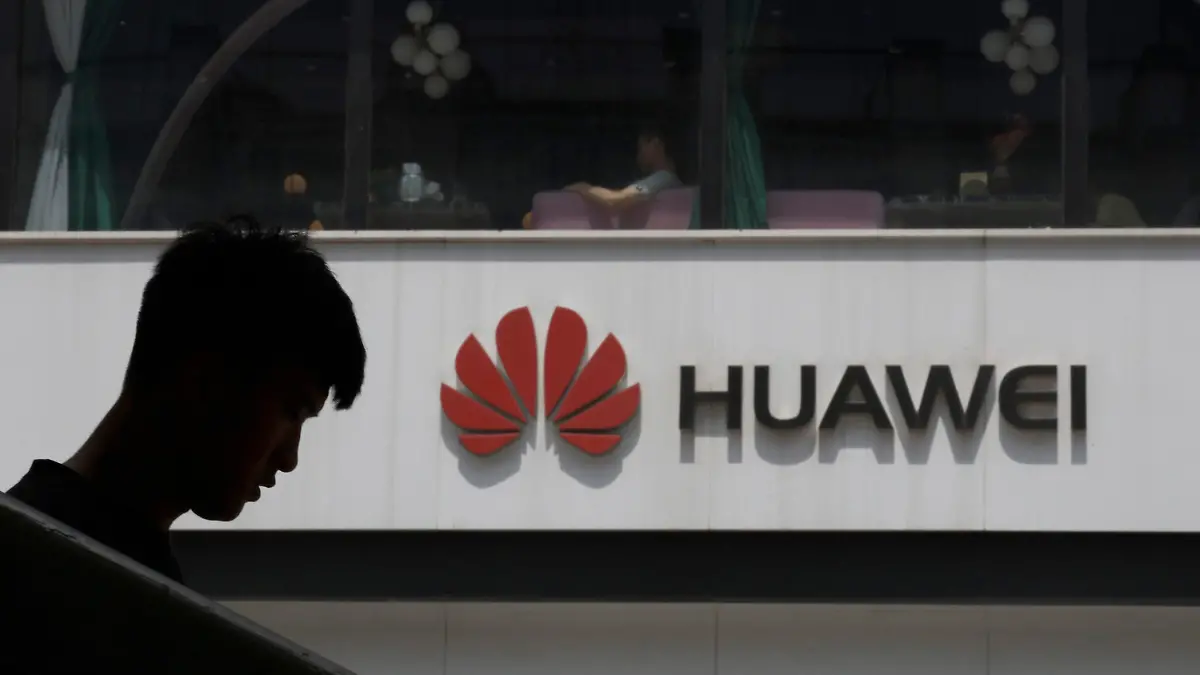 FILE - In this Thursday, May 16, 2019 file photo, a man is silhouetted near the Huawei logo in Beijing. Struggling under U.S. sanctions, Chinese tech giant Huawei has unveiled a new flagship foldable smartphone but says it will only be sold in China. (AP Photo/Ng Han Guan, File)