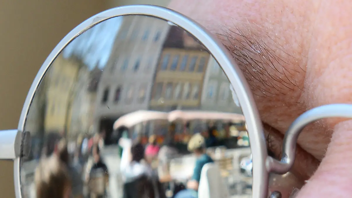 Eine Straßenszene spiegelt sich am 15.04.2013 bei sonnigem Wetter in der Sonnenbrille eines Gastes in einem Cafe in Bamberg (Bayern). Foto: David Ebener/dpa | Verwendung weltweit