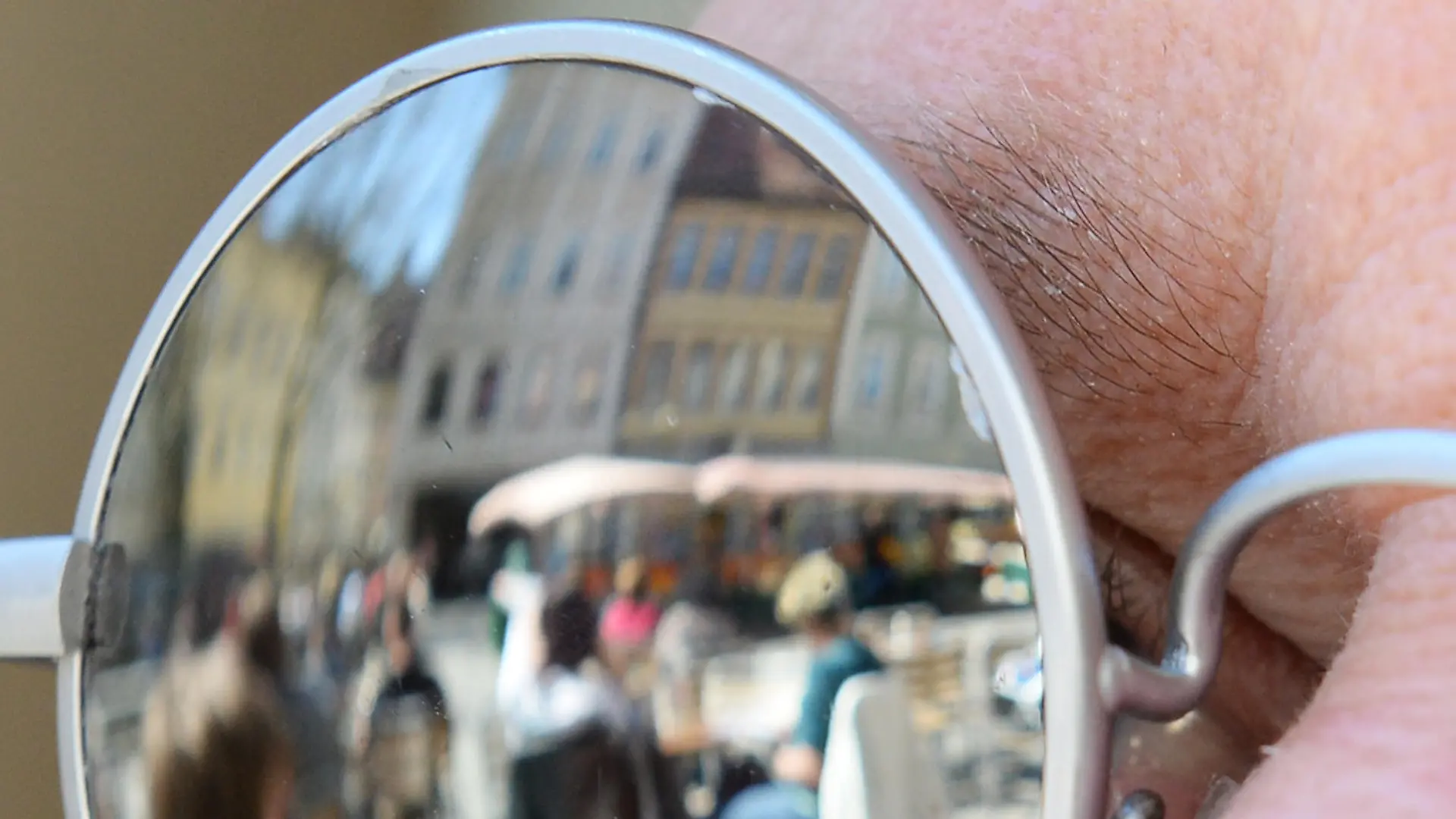 Eine Straßenszene spiegelt sich am 15.04.2013 bei sonnigem Wetter in der Sonnenbrille eines Gastes in einem Cafe in Bamberg (Bayern). Foto: David Ebener/dpa | Verwendung weltweit