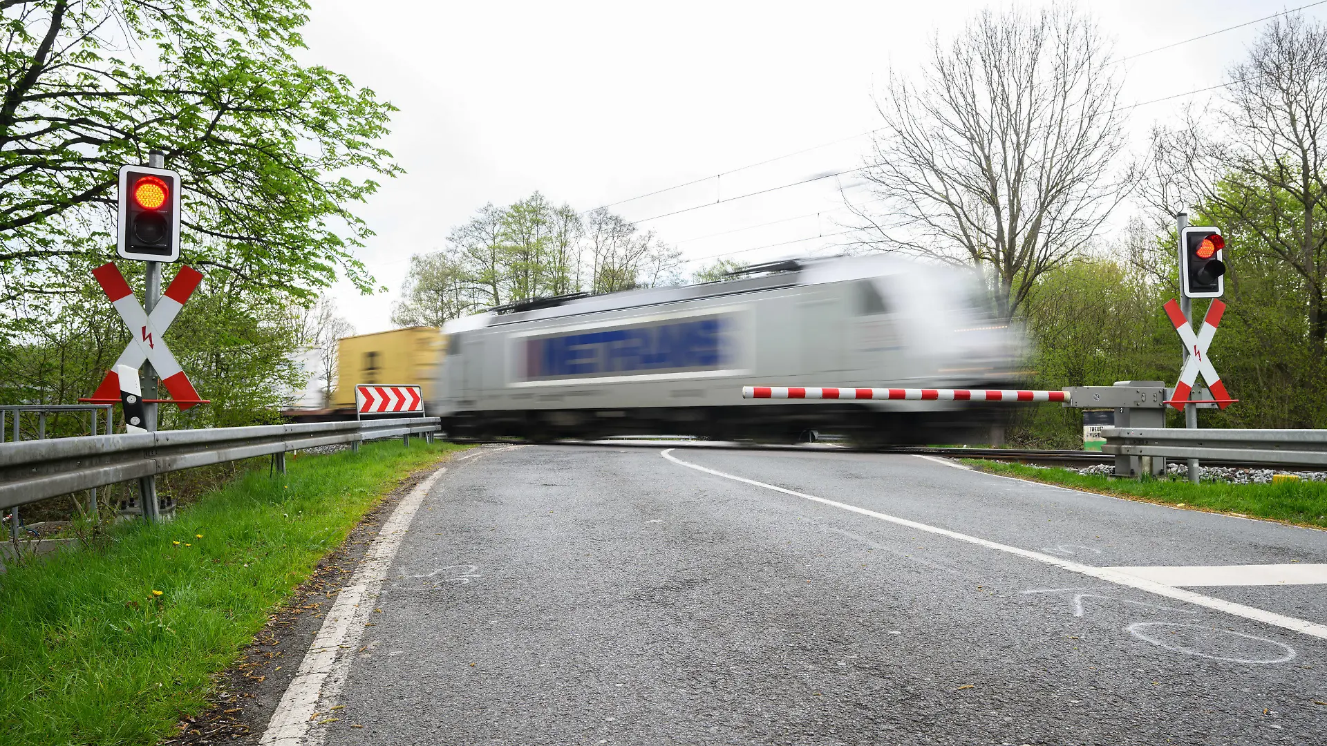 24.04.2023, Niedersachsen, Neustadt am Rübenberge: Ein Zug passiert den Bahnübergang, an dem am Sonntagmorgen ein Auto von einem Zug erfasst worden war. Nach dem tödlichen Unfall in der Region Hannover setzt die Polizei alles daran, die Ursache zu klären. Bei dem Unfall waren am frühen Sonntagmorgen (23.04.2023) drei junge Menschen gestorben, als ihr Auto auf dem Bahnübergang von einer Regionalbahn erfasst wurde. Nach Polizeiangaben waren sie trotz geschlossener Halbschranken auf den Bahnübergang gefahren. Foto: Julian Stratenschulte/dpa +++ dpa-Bildfunk +++