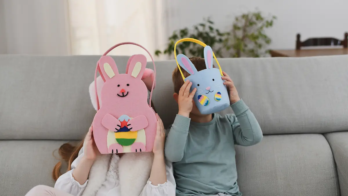 Kinder verstecken ihr Gesicht hinter ihren Oster-Geschenken.
