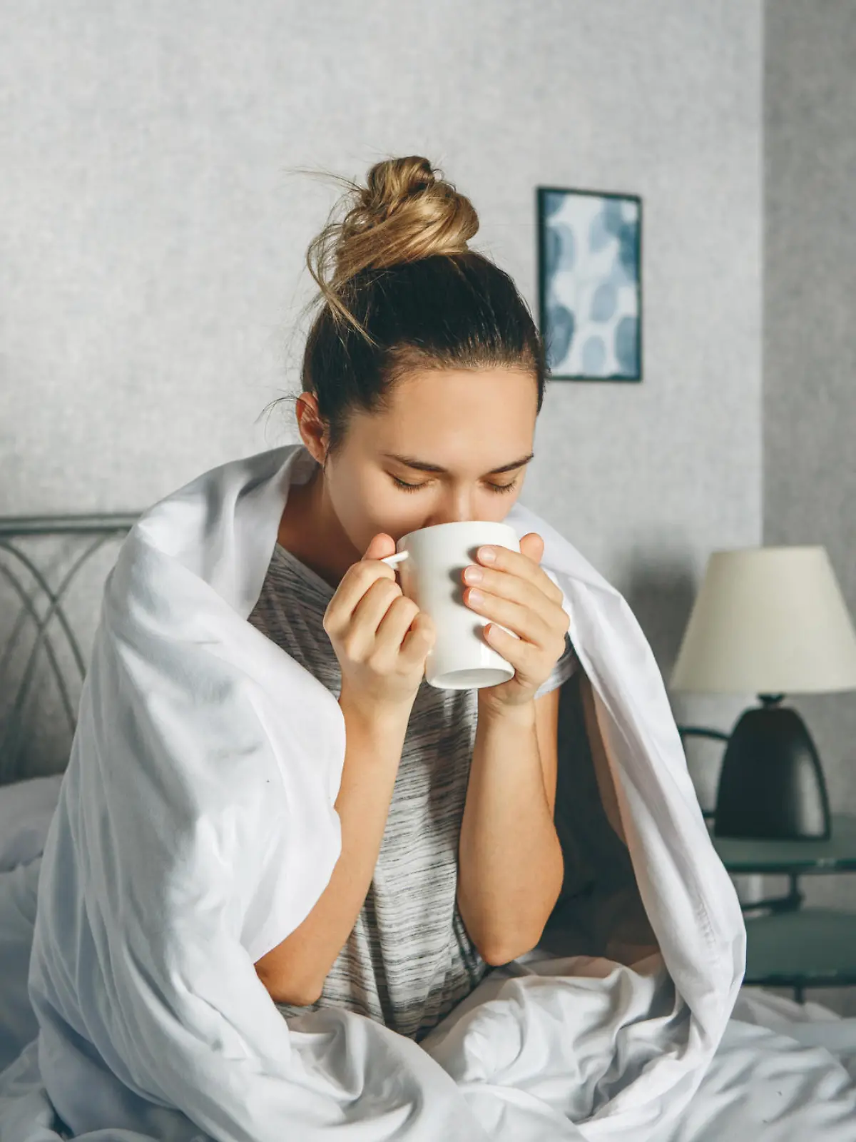 Frau trinkt morgens Kaffee im Bett