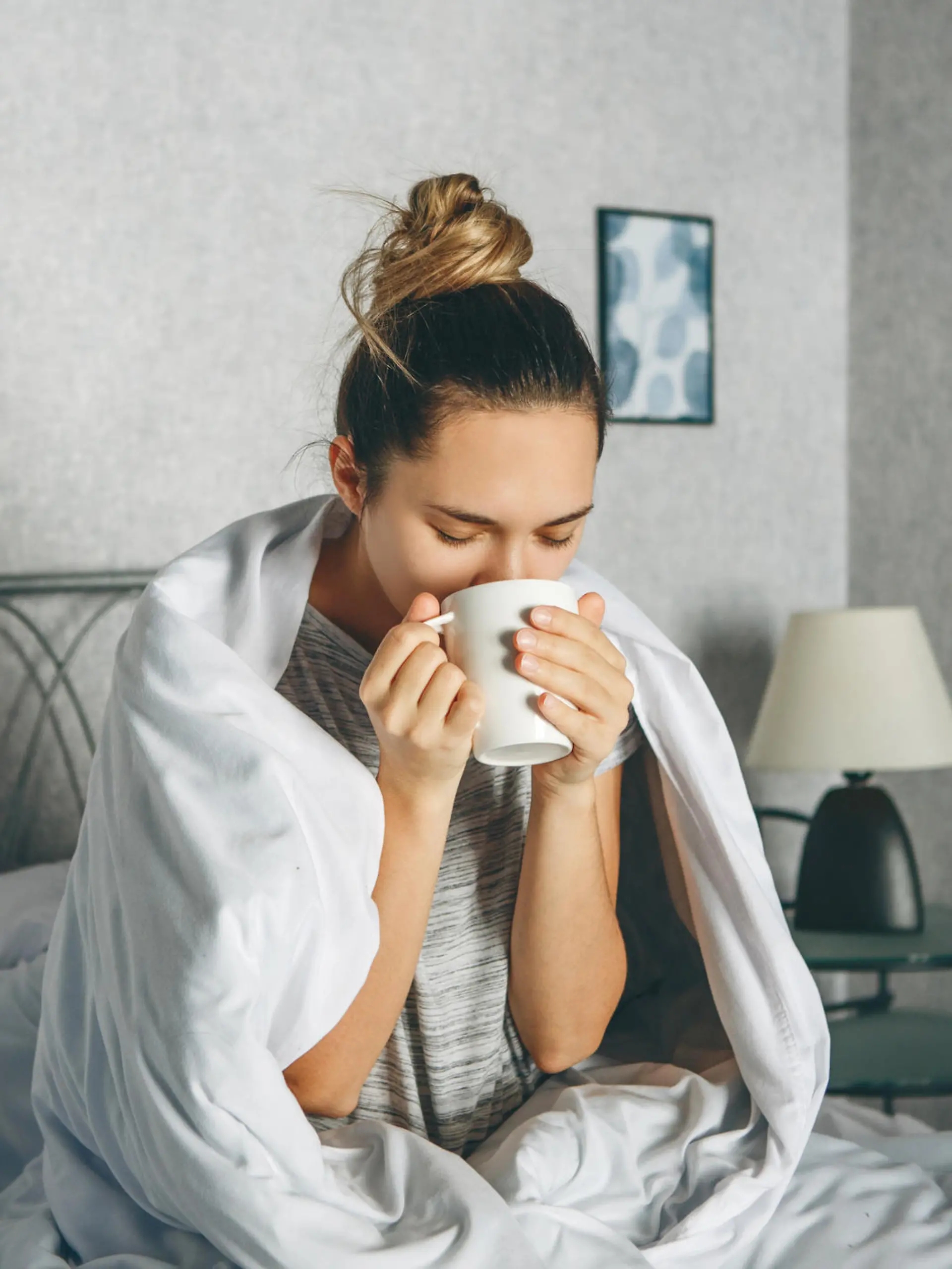Frau trinkt morgens Kaffee im Bett