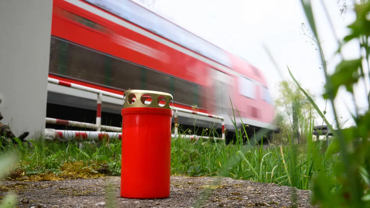 24.04.2023, Niedersachsen, Neustadt am Rübenberge: Eine Kerze steht am Bahnübergang, an dem am Sonntagmorgen ein Auto von einem Zug erfasst worden war. Nach dem tödlichen Unfall in der Region Hannover setzt die Polizei alles daran, die Ursache zu klären. Bei dem Unfall waren am frühen Sonntagmorgen (23.04.2023) drei junge Menschen gestorben, als ihr Auto auf dem Bahnübergang von einer Regionalbahn erfasst wurde. Nach Polizeiangaben waren sie trotz geschlossener Halbschranken auf den Bahnübergang gefahren. Foto: Julian Stratenschulte/dpa +++ dpa-Bildfunk +++