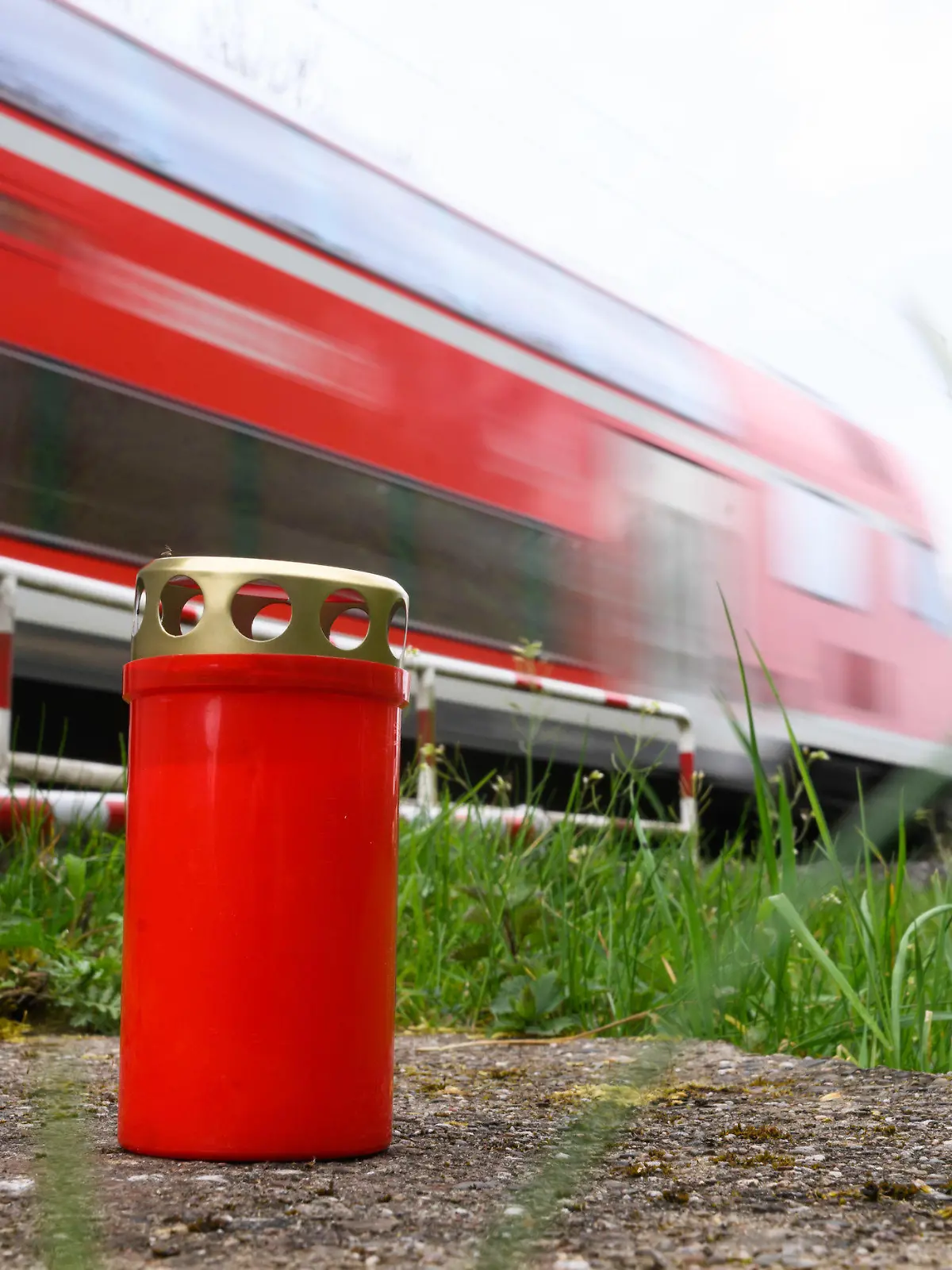 24.04.2023, Niedersachsen, Neustadt am Rübenberge: Eine Kerze steht am Bahnübergang, an dem am Sonntagmorgen ein Auto von einem Zug erfasst worden war. Nach dem tödlichen Unfall in der Region Hannover setzt die Polizei alles daran, die Ursache zu klären. Bei dem Unfall waren am frühen Sonntagmorgen (23.04.2023) drei junge Menschen gestorben, als ihr Auto auf dem Bahnübergang von einer Regionalbahn erfasst wurde. Nach Polizeiangaben waren sie trotz geschlossener Halbschranken auf den Bahnübergang gefahren. Foto: Julian Stratenschulte/dpa +++ dpa-Bildfunk +++