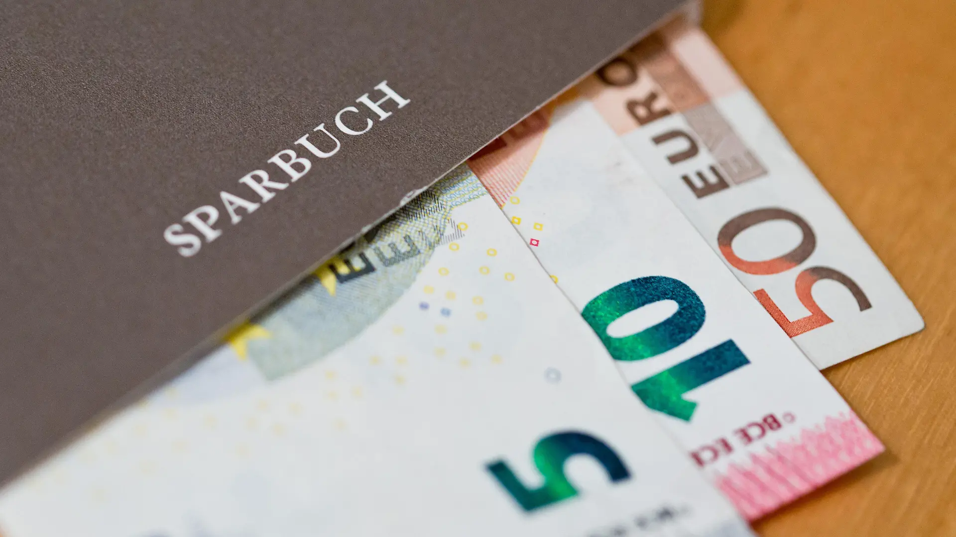 ARCHIV - 15.03.2016, Bayern, Nürnberg: ILLUSTRATION - Geldscheine (Euro) liegen in einem Sparbuch. Größere Summen auf dem Tagesgeldkonto können zunehmend ins Geld gehen. Die Zahl der Banken und Sparkassen, die Kunden dafür Negativzinsen aufbürden, hat sich einer Auswertung des Vergleichsportals Verivox zufolge innerhalb von zwölf Monaten nahezu verzehnfacht. (zu dpa «Trend zu Negativzinsen für hohe Sparsummen beschleunigt sich») Foto: Daniel Karmann/dpa +++ dpa-Bildfunk +++