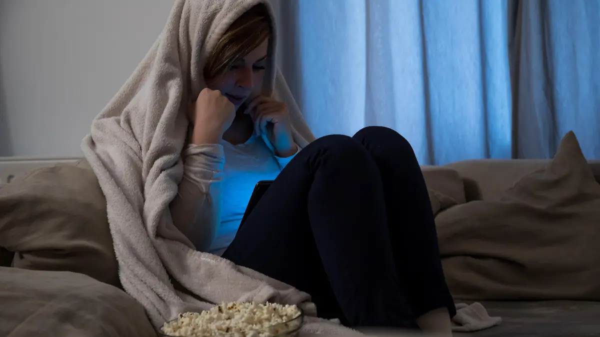 Junge Frau gruselt sich beim Schauen eines Horrorfilms