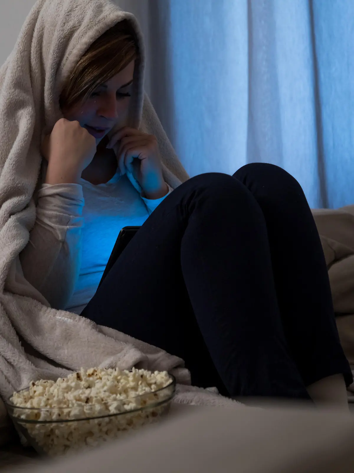 Junge Frau gruselt sich beim Schauen eines Horrorfilms