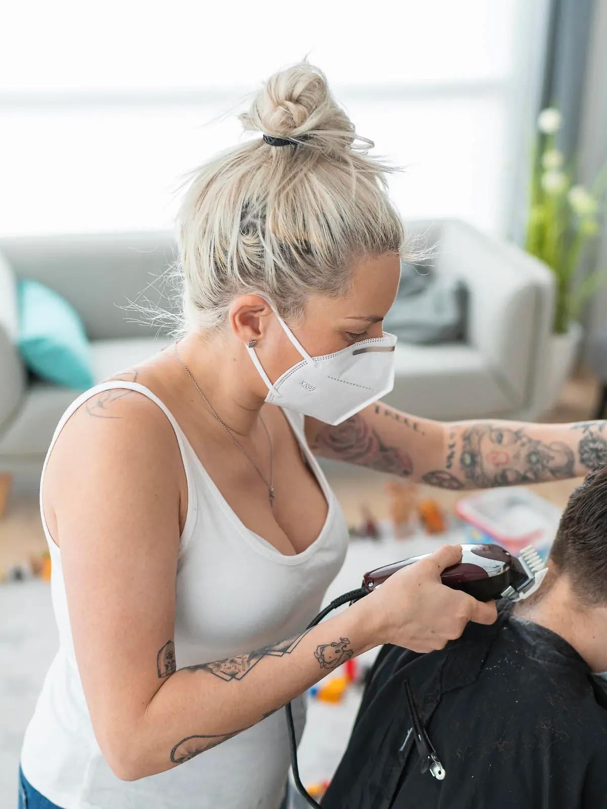  Female hairdresser wearing mask cutting boy s hair with electric razor at home during curfew model released Symbolfoto property released SNF00367