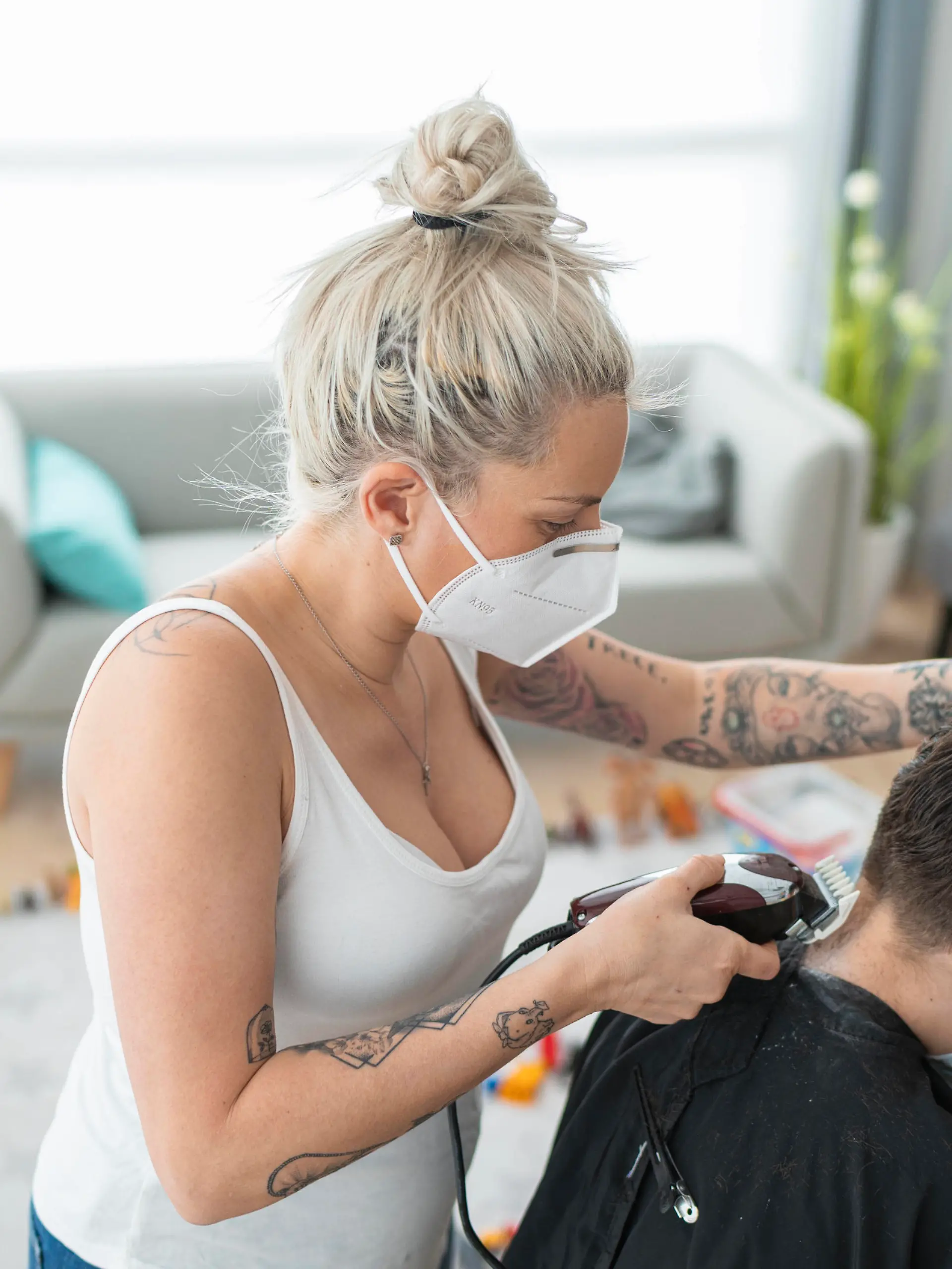  Female hairdresser wearing mask cutting boy s hair with electric razor at home during curfew model released Symbolfoto property released SNF00367