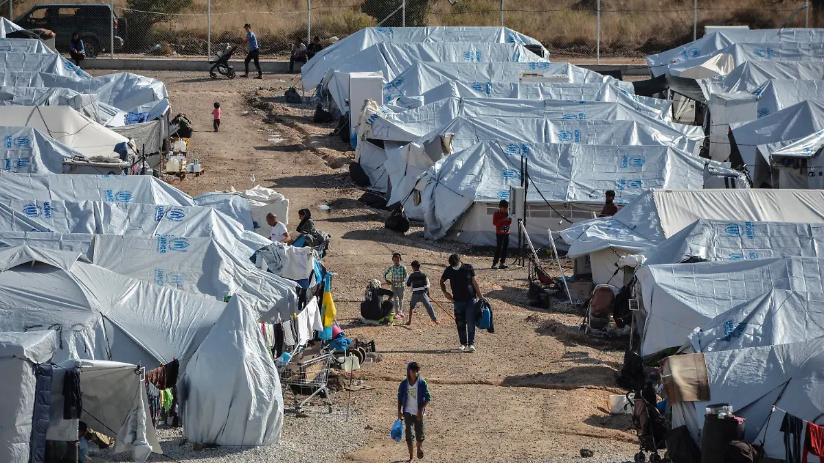 FILE - In this Wednesday, Oct. 14, 2020, file photo, migrants walk after a rainstorm at the Kara Tepe refugee camp, on the northeastern Aegean island of Lesbos, Greece. The anti-torture committee of the Council of Europe, the continent's main human rights organization, on Thursday, Nov. 19, 2020 has slammed conditions under which migrants are held in some detention centers in Greece and voiced concern over persistent allegations the country conducts illegal pushbacks of migrants. (AP Photo/Panagiotis Balaskas, File)