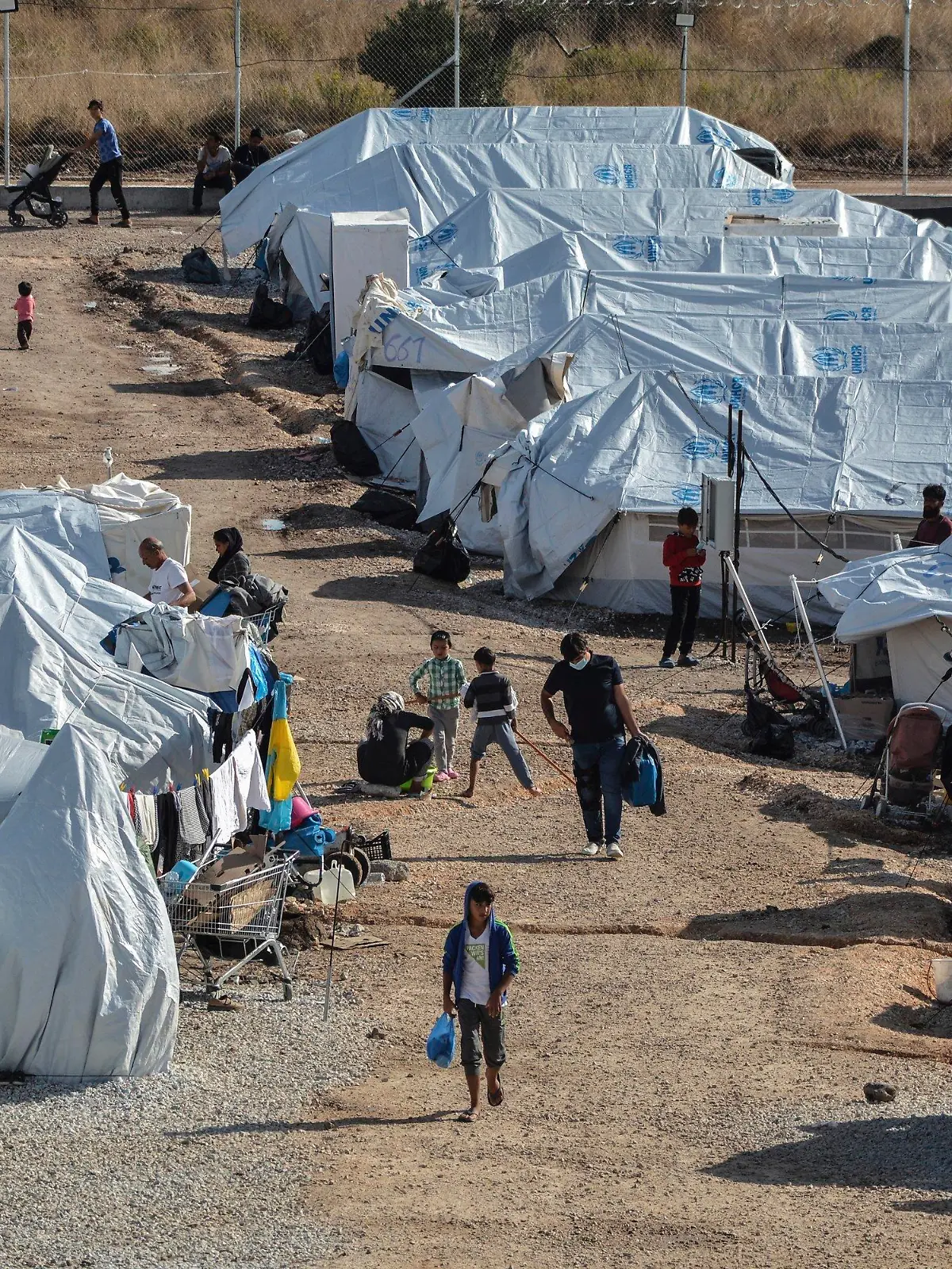 FILE - In this Wednesday, Oct. 14, 2020, file photo, migrants walk after a rainstorm at the Kara Tepe refugee camp, on the northeastern Aegean island of Lesbos, Greece. The anti-torture committee of the Council of Europe, the continent's main human rights organization, on Thursday, Nov. 19, 2020 has slammed conditions under which migrants are held in some detention centers in Greece and voiced concern over persistent allegations the country conducts illegal pushbacks of migrants. (AP Photo/Panagiotis Balaskas, File)