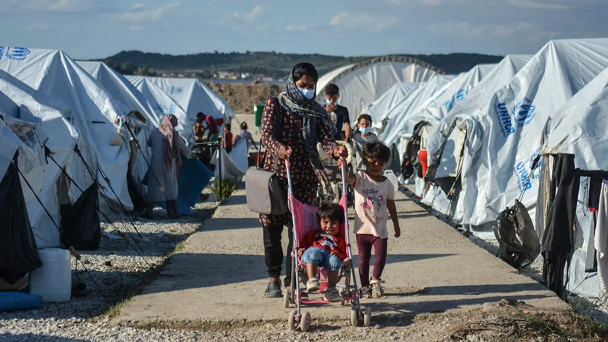 Migrants walk after a rainstorm at the Kara Tepe refugee camp, on the northeastern Aegean island of Lesbos, Greece, Wednesday, Oct. 14, 2020. Around 7,600 refugees and migrants have settled at the new tent city after successive fires on Sept. 9, devastated the Moria refugee camp, making thousands of inhabitants homeless during a COVD-19 lockdown. (AP Photo/Panagiotis Balaskas)