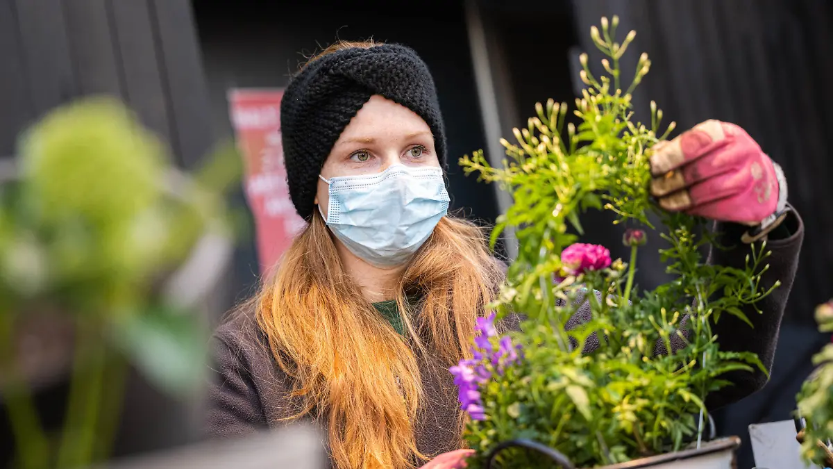 13.02.2021, Niedersachsen, Oldenburg: Alexandra Stahnke, Mitarbeiterin im Oldenburger Wohngarten, bereitet einen Blumentopf für den Verkauf vor. Foto: Mohssen Assanimoghaddam/dpa +++ dpa-Bildfunk +++