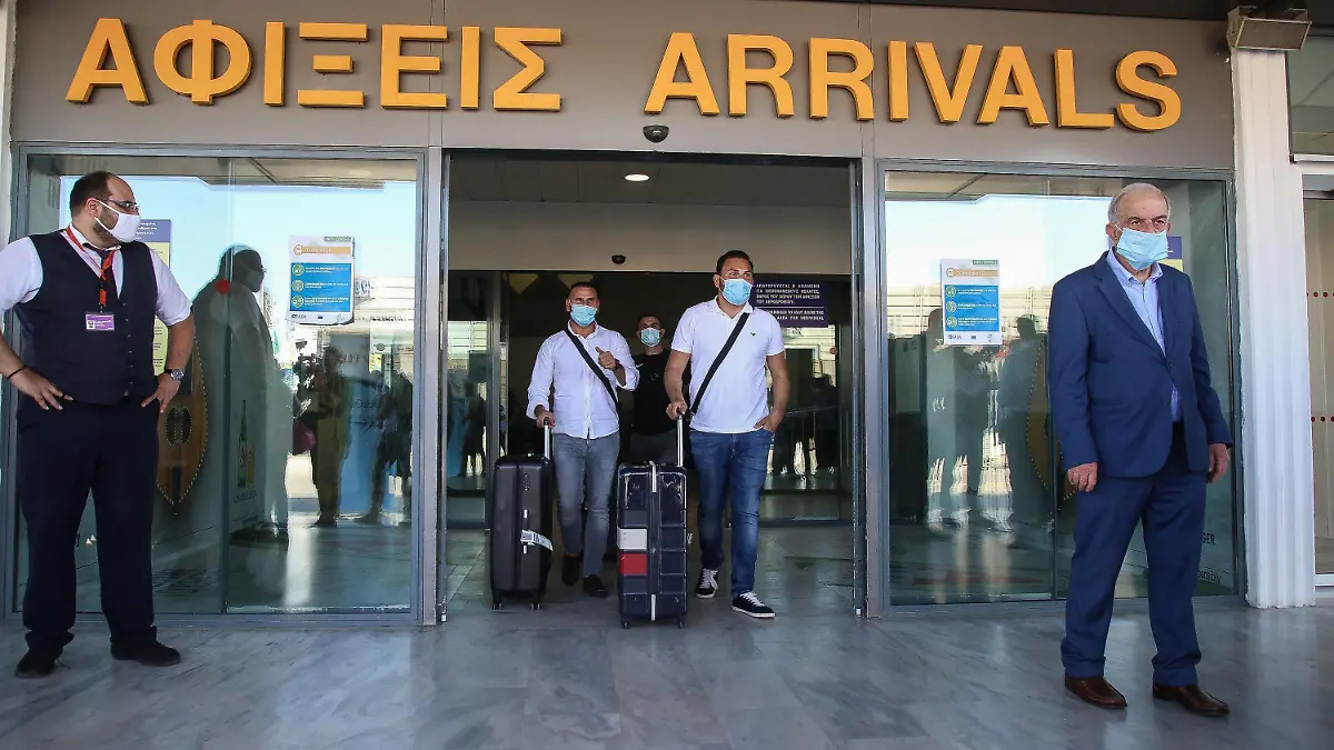 01.07.2020, Griechenland, Iraklion: Touristen mit medizinischem Mundschutz kommen am internationalen Flughafen der griechischen Insel Kreta an. Landesweit wurden alle Flughäfen für Auslandsflüge geöffnet. Erstmals nach Ausbruch der Corona-Pandemie sind Charterflugzeuge aus Deutschland auf dem Flughafen von Kreta gelandet und wurden feierlich mit Musikanten und den lokalen Schnaps Tsikoudiá empfangen. Foto: Eurokinissi/Eurokinissi via ZUMA Wire/dpa +++ dpa-Bildfunk +++