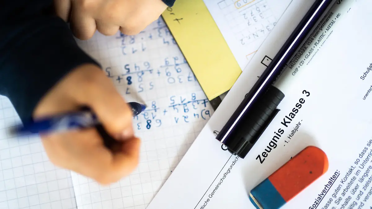 29.01.2021, Nordrhein-Westfalen, Wetter: ILLUSTRATION - Eine Schülerin der dritten Klasse arbeitet an ihrem Schreibtisch, während ihr Zeugnis auf ihrem Schreibtisch liegt. (gestellte Szene) Mitten im coronabedingten Distanzunterricht erhalten 2,5 Millionen Schüler in Nordrhein-Westfalen ihre Halbjahreszeugnisse. Foto: Jonas Güttler/dpa +++ dpa-Bildfunk +++