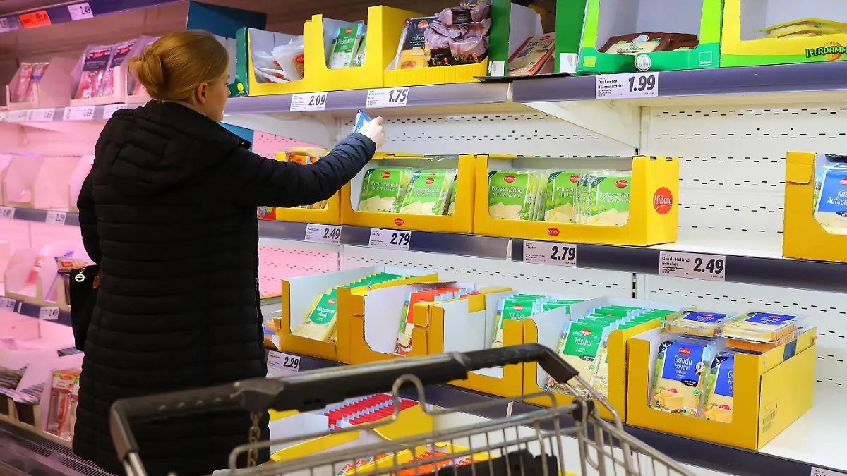 Die aktuelle Inflationsrate kommt auch im Supermarkt an, wo für die Bürgerinnen und Bürger vieles teurer wird. Eine Frau steht an der Kühltheke und vergleicht die Preise.