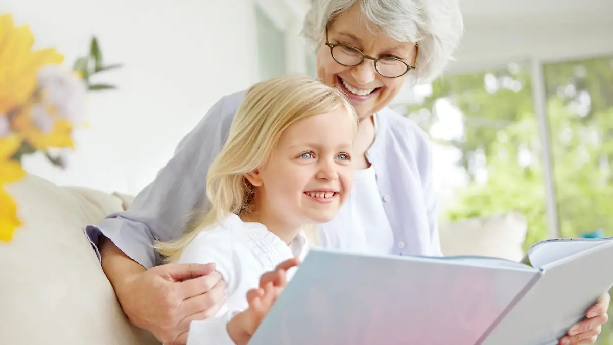 A cute little girl reading a book with her grandmother