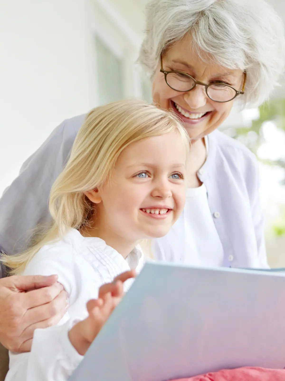 A cute little girl reading a book with her grandmother
