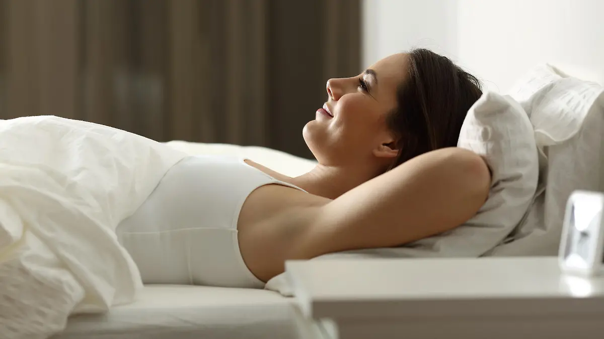 Frau liegt zugedeckt im Bett