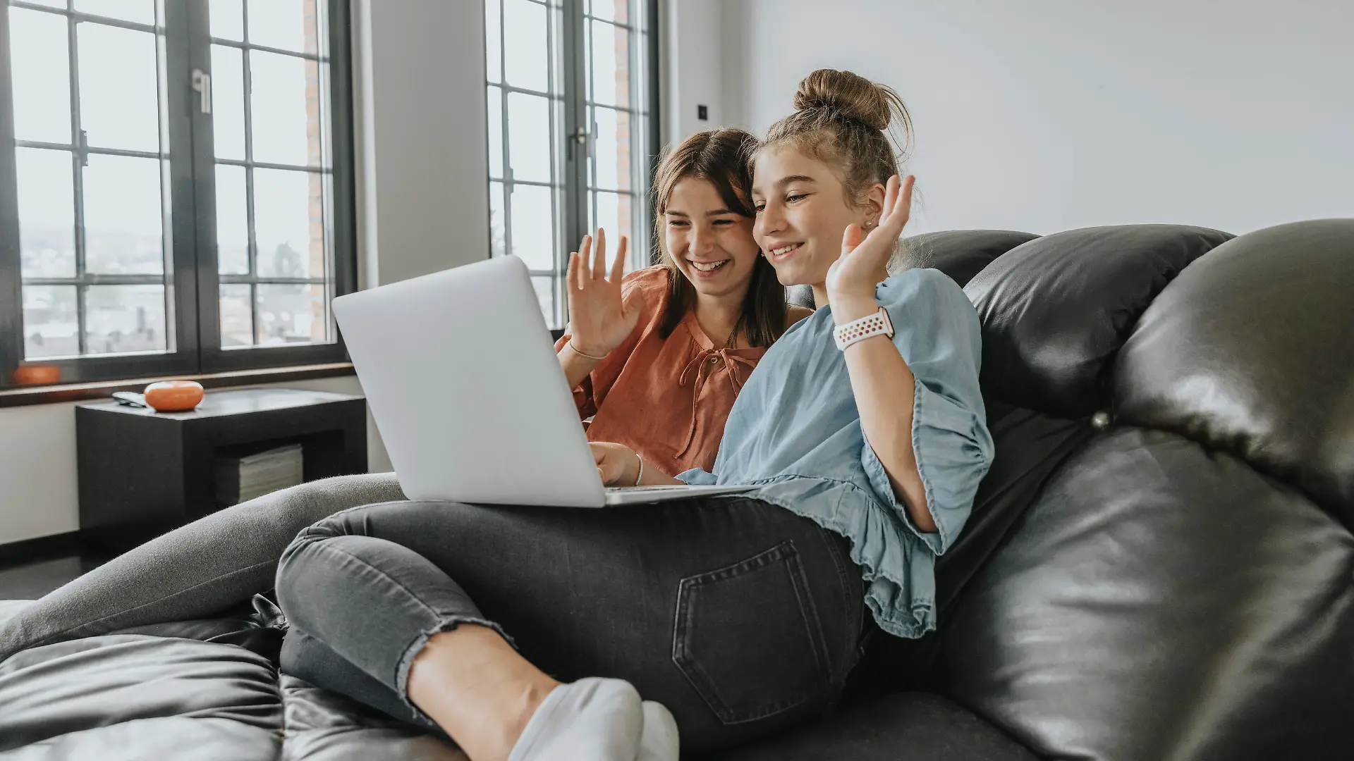  Friends waving while video conferencing over laptop on sofa at home model released Symbolfoto property released MFF06109