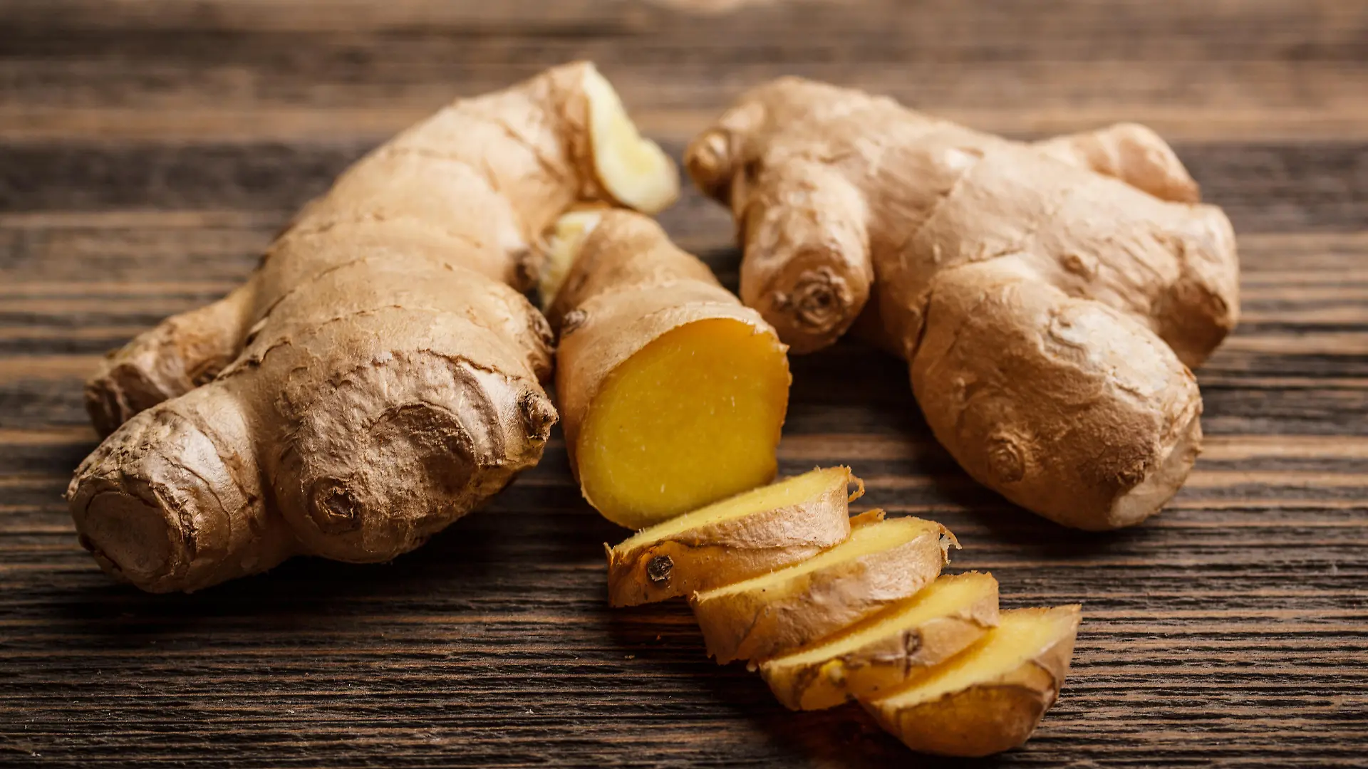 Fresh ginger, whole and sliced on rustic wooden background