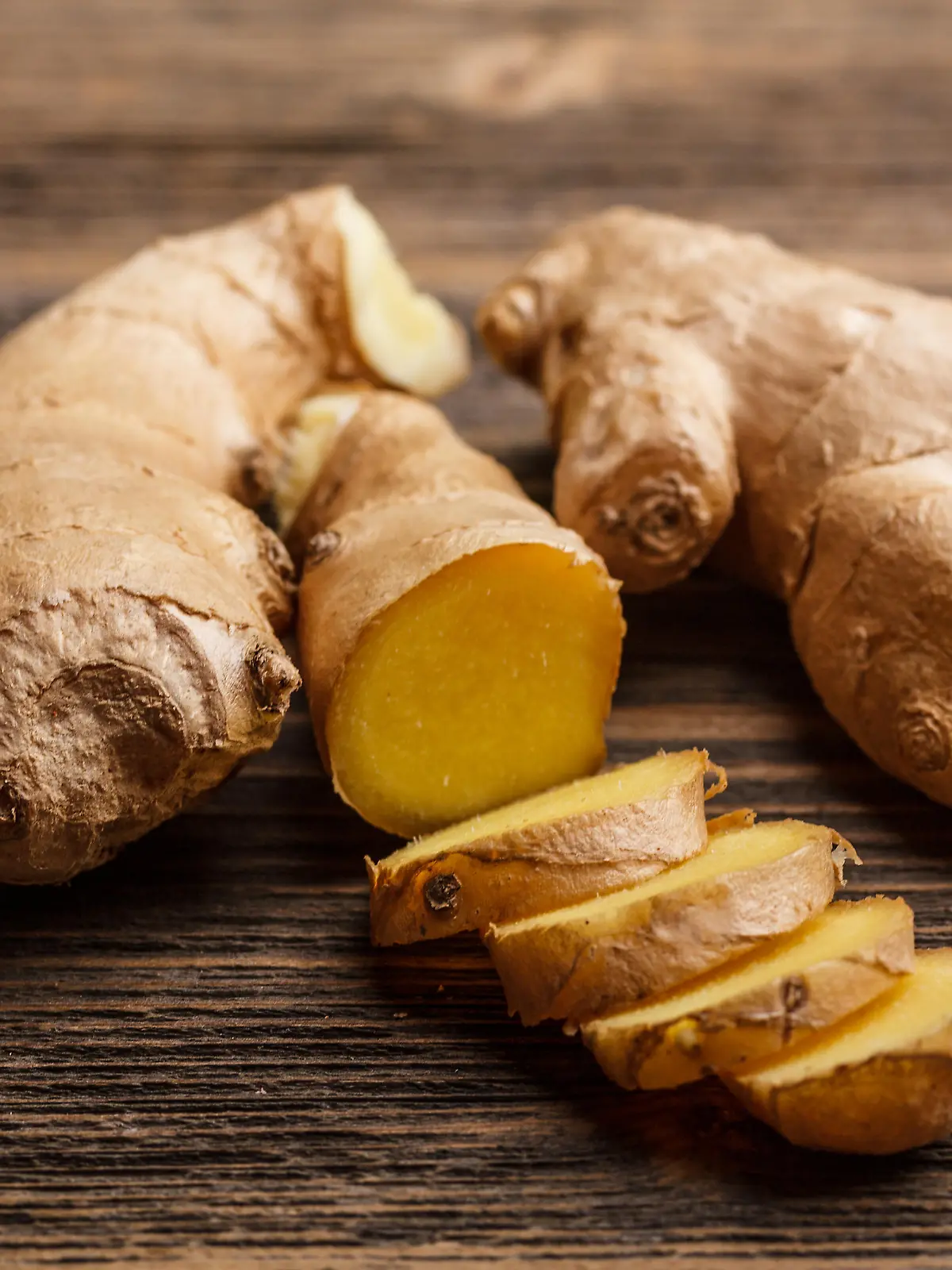 Fresh ginger, whole and sliced on rustic wooden background