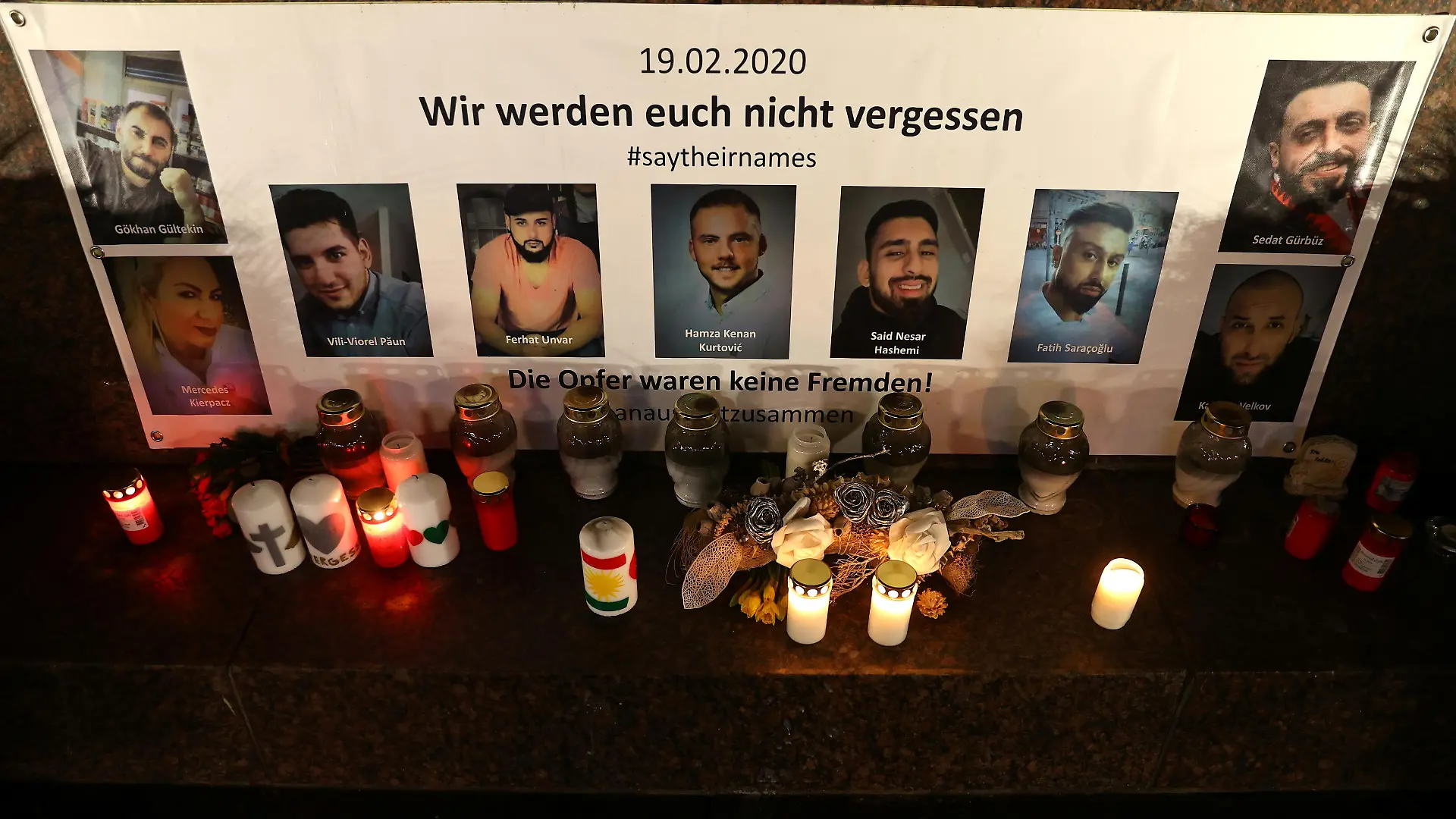Pictures of the victims and candles are seen at the statue of German writers brothers Grimm one night ahead of the first anniversary of an attack where a man, who had posted a racist manifesto online, shot dead nine people in Hanau, Germany, February 18, 2021. REUTERS/Kai Pfaffenbach