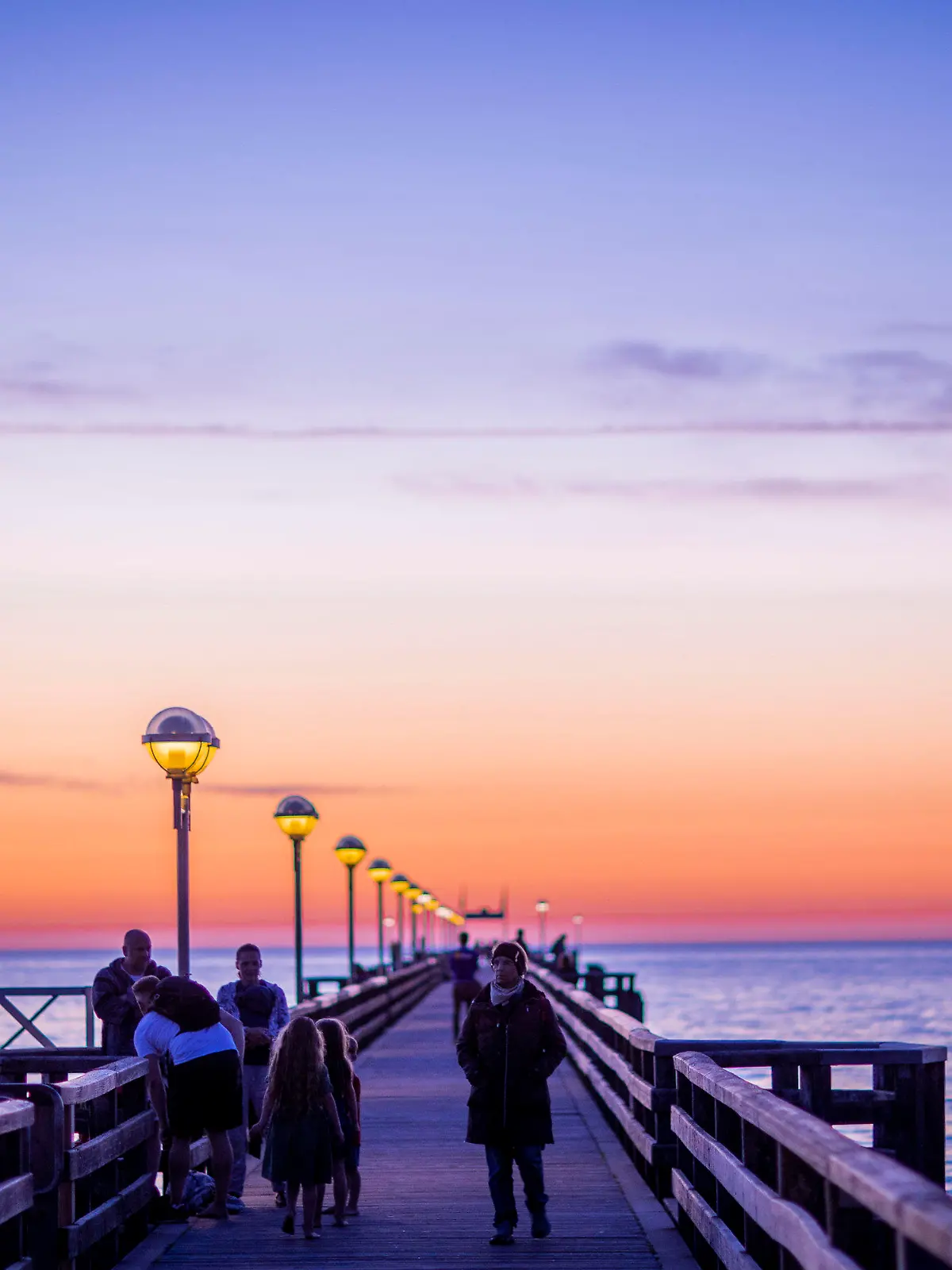 ARCHIV - 24.06.2020, Mecklenburg-Vorpommern, Graal-Müritz: Urlauber sind nach Sonnenuntergang auf der Seebrücke unterwegs. Nach einer wegen der Corona-Pandemie völlig vermurksten Saison steht für die Tourismusbranche nun im Herbst der Endspurt an. (zu dpa «Tourismusbranche hofft auf Endspurt im Herbst») Foto: Jens Büttner/dpa-Zentralbild/dpa +++ dpa-Bildfunk +++