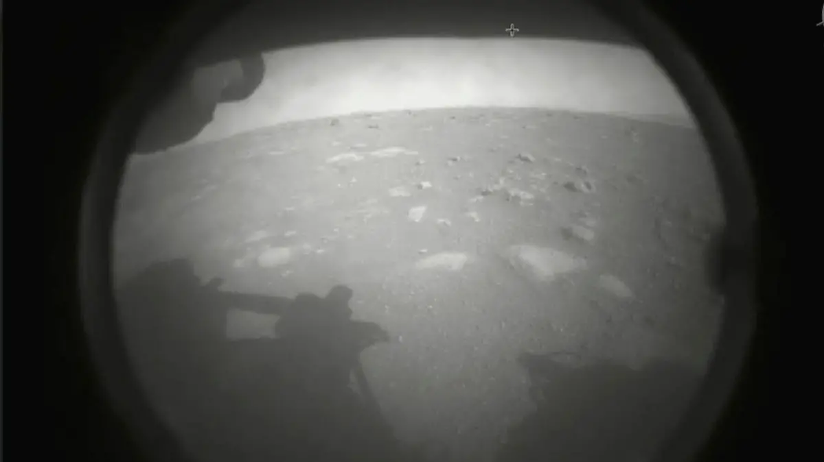 dpatopbilder - HANDOUT - 18.02.2021, ---, -: Das von der NASA zur Verfügung gestellte Foto zeigt das erste vom Perseverance-Rover gesendete Bild der Marsoberfläche, kurz nach der Landung im Jezero-Krater. Foto: -/NASA/AP/dpa - ACHTUNG: Nur zur redaktionellen Verwendung und nur mit vollständiger Nennung des vorstehenden Credits +++ dpa-Bildfunk +++