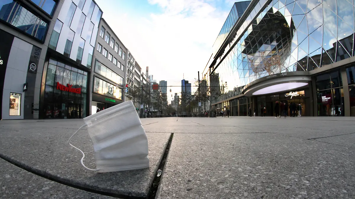 Getragene Mund-Nase-Bedeckungsmaske liegt auf dem Pflaster der menschenleeren Fußgängerzone und Einkaufsstraße Zeil in der Innenstadt von Frankfurt, Hessen, Deutschland *** Worn mouth nose covering mask lies on the pavement of the deserted pedestrian zone and shopping street Zeil in downtown Frankfurt, Hesse, Germany