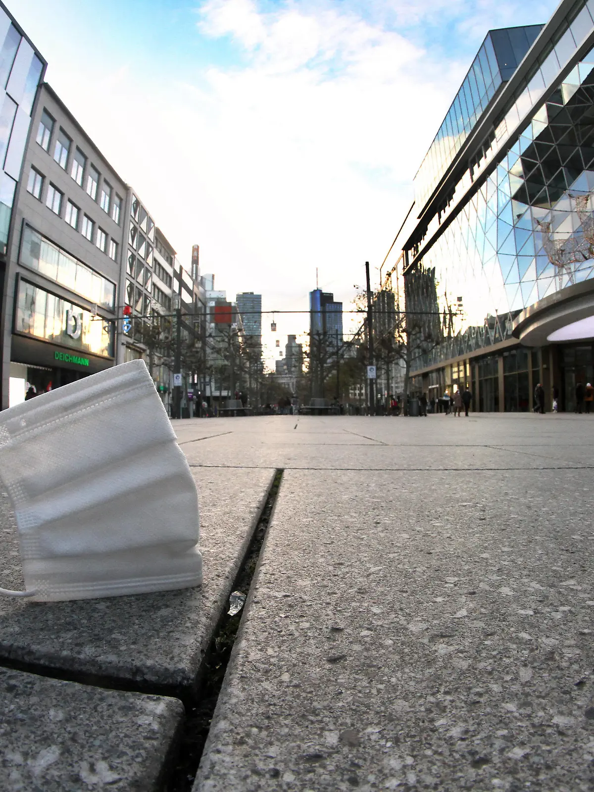 Getragene Mund-Nase-Bedeckungsmaske liegt auf dem Pflaster der menschenleeren Fußgängerzone und Einkaufsstraße Zeil in der Innenstadt von Frankfurt, Hessen, Deutschland *** Worn mouth nose covering mask lies on the pavement of the deserted pedestrian zone and shopping street Zeil in downtown Frankfurt, Hesse, Germany 