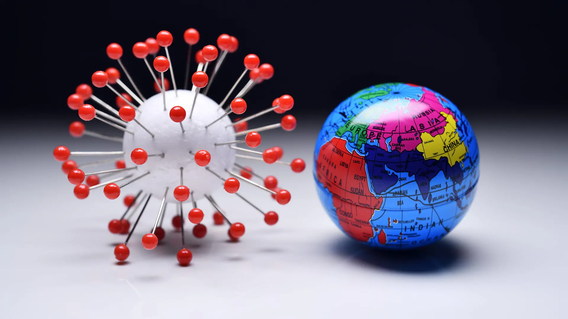 Coronavirus-Modell und Erdkugel, weltweite Pandemie und Pandemie-Bekämpfung *** Coronavirus model and globe, global pandemic and pandemic control