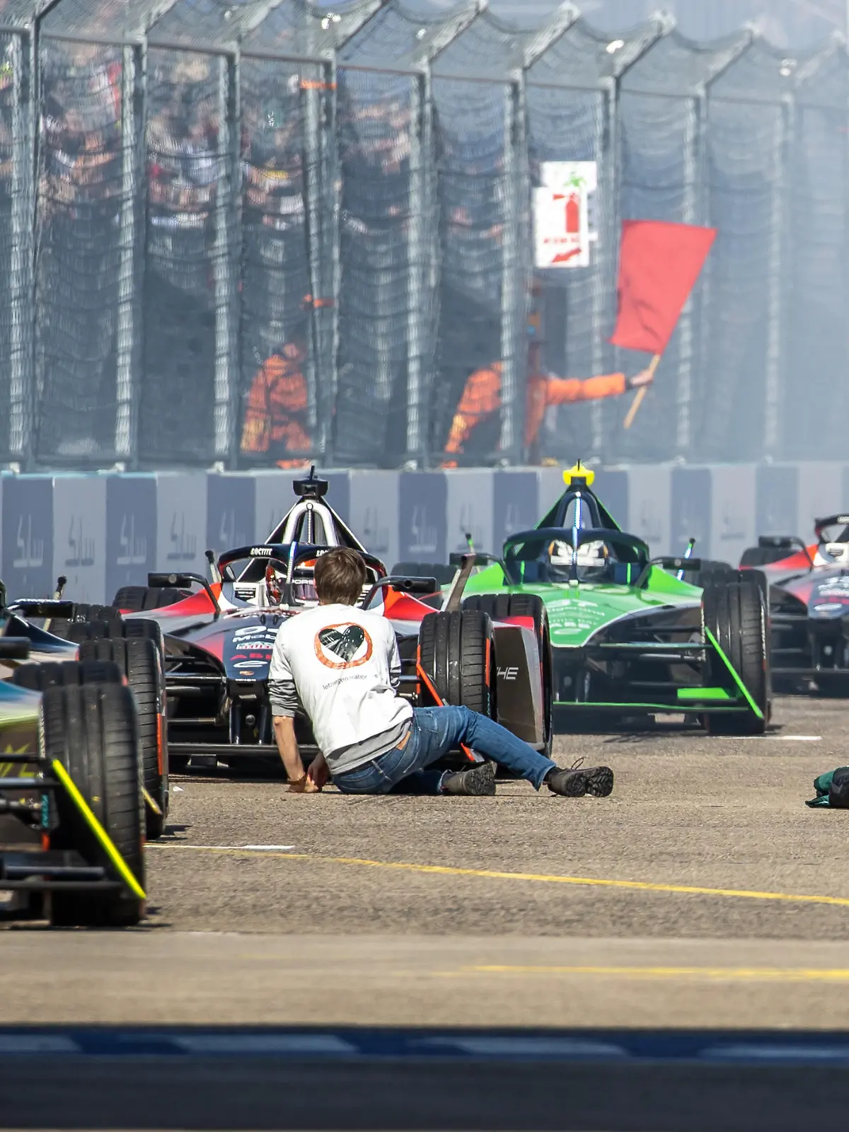 Motorsport: Formel-E: Berlin E-Prix am Tempelhofer Feld, Rennen: Klimaaktivisten der letzten Generation sitzen vor den Startbereiten Rennwagen auf der Strecke.