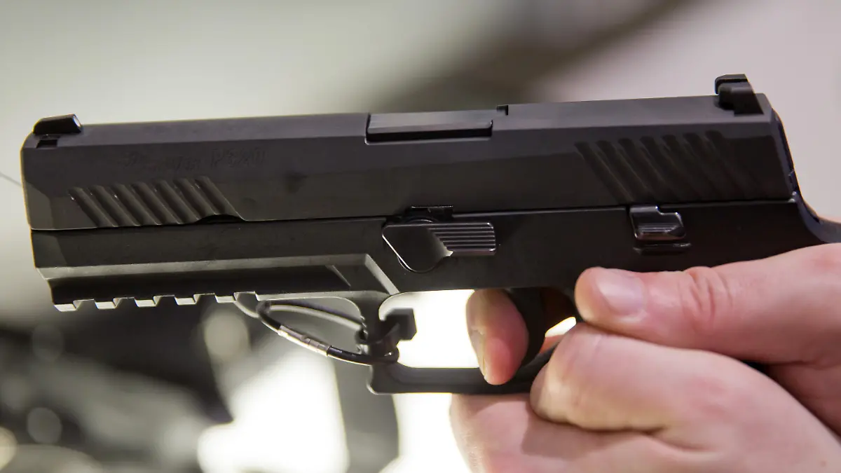 Ein Messebesucher hält eine Ausführung der Pistole vom Typ P320 des Waffenherstellers SIG Sauer GmbH & Co. KG am 05.03.2016 auf der Jagd- und Sportwaffenmesse IWA OutdoorClassics in Nürnberg (Bayern) am Stand des Unternehmens in der Hand. Foto: Daniel Karmann
