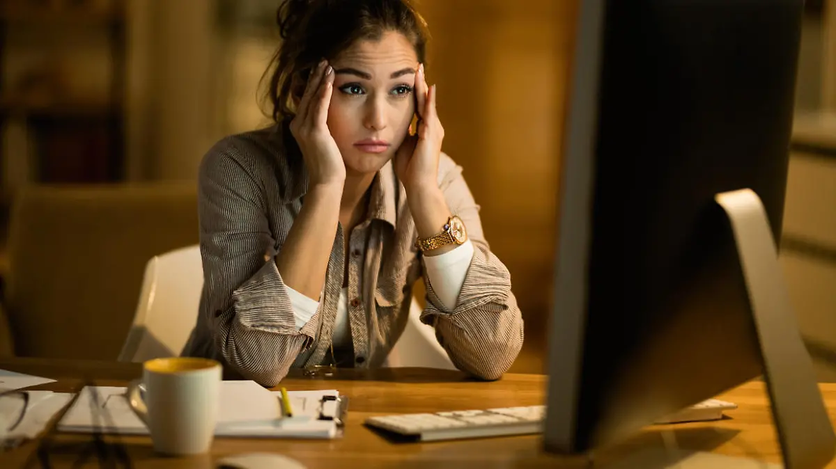 Young woman feeling confused while working late and reading something on a computer at home.