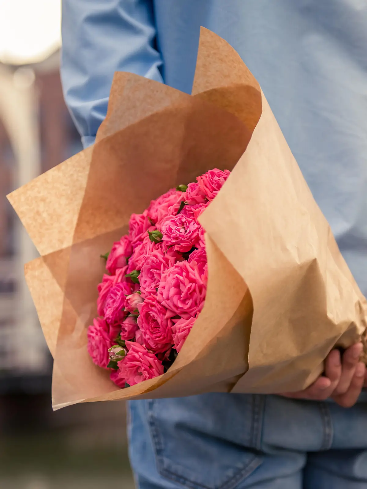 Mann hält einen großen Blumenstrauß hinter dem Rücken.