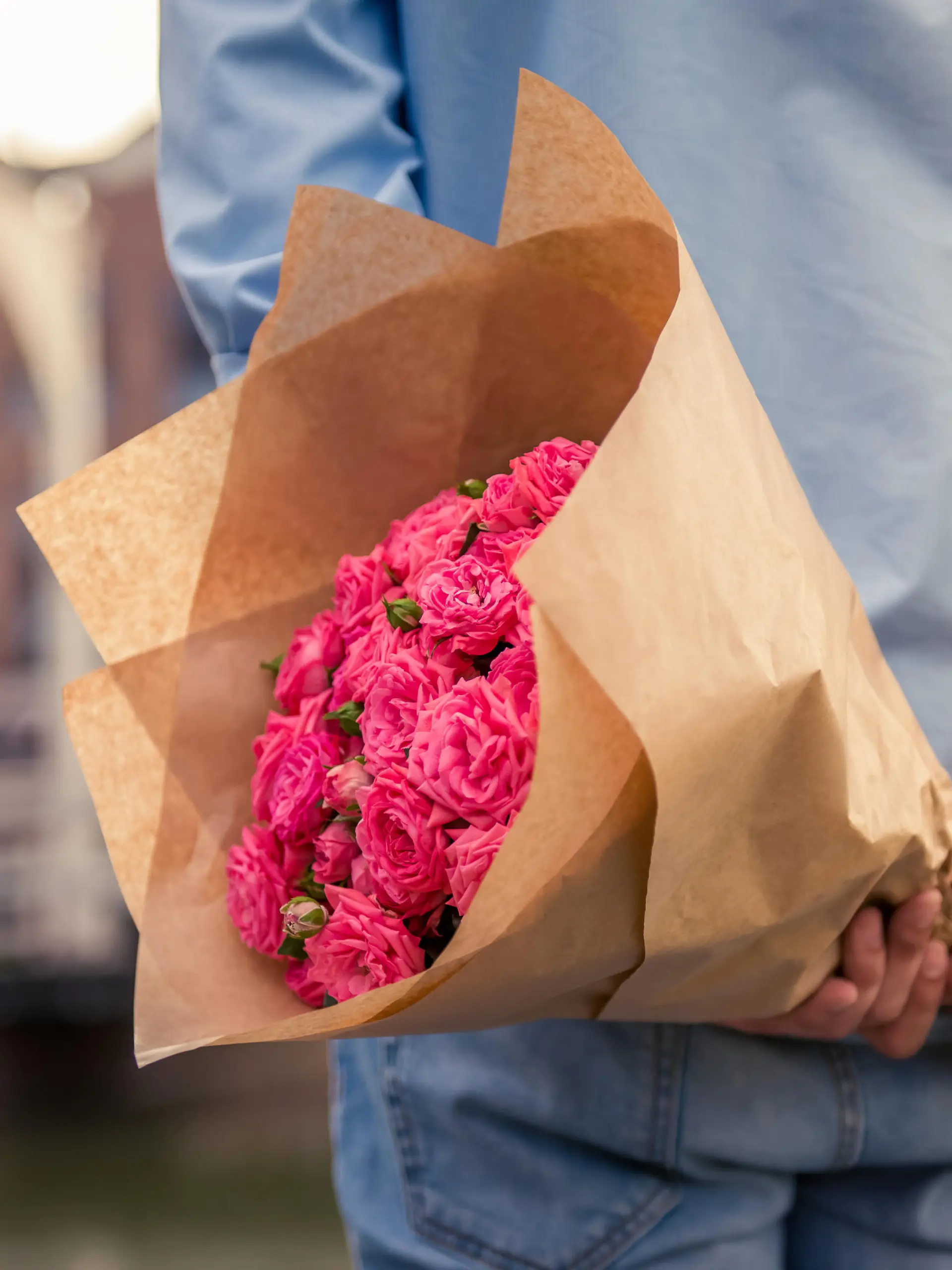 Mann hält einen großen Blumenstrauß hinter dem Rücken.