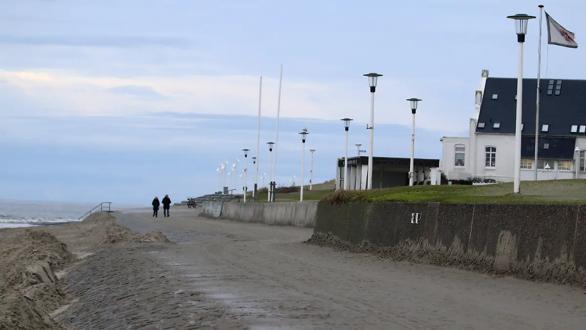 01.01.2021, Niedersachsen, Norderney: Spaziergänger sind am Weststrand der Nordsee-Insel unterwegs. Das neue Jahre startete mit Temperaturen um fünf Grad grau und windig. Foto: Volker Bartels/dpa +++ dpa-Bildfunk +++