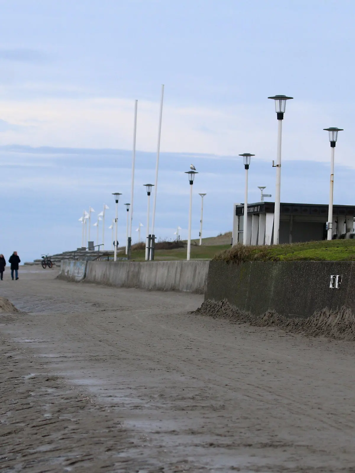 01.01.2021, Niedersachsen, Norderney: Spaziergänger sind am Weststrand der Nordsee-Insel unterwegs. Das neue Jahre startete mit Temperaturen um fünf Grad grau und windig. Foto: Volker Bartels/dpa +++ dpa-Bildfunk +++