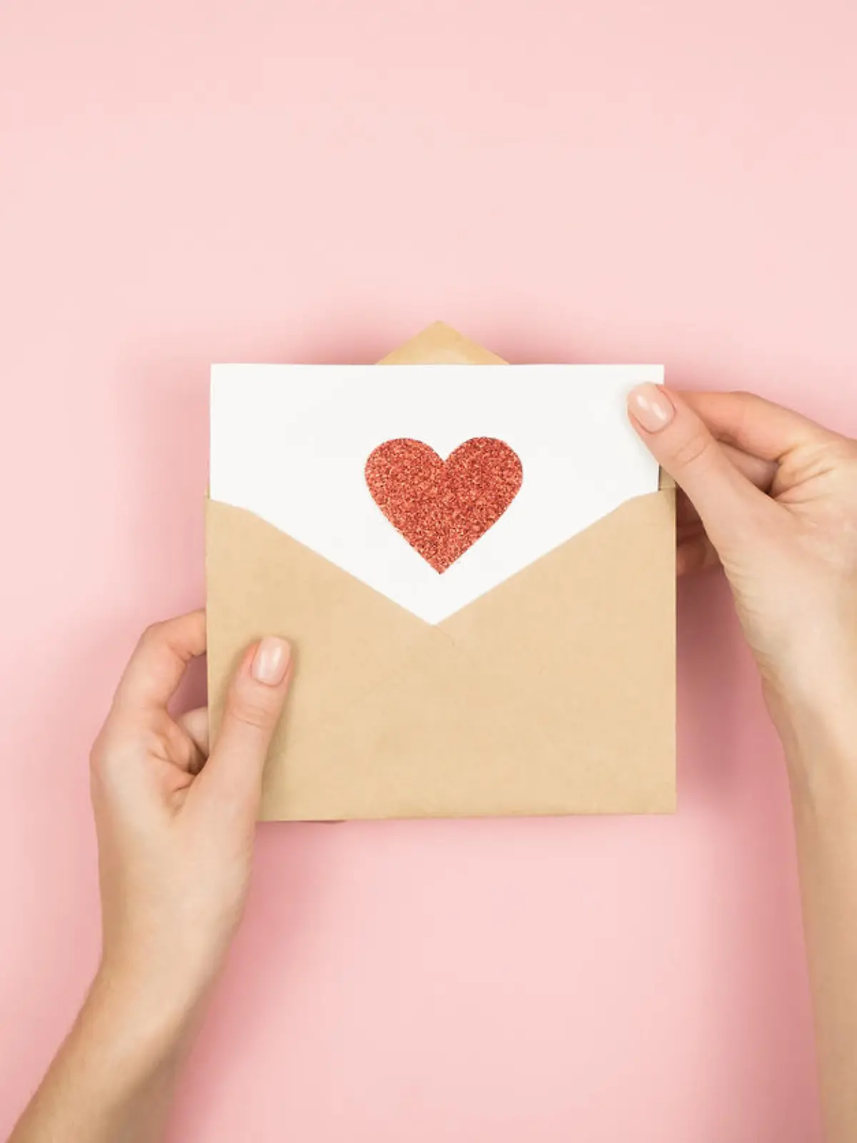 Brief mit Herz wird zum Valentinstag von Frauenhänden verpackt
