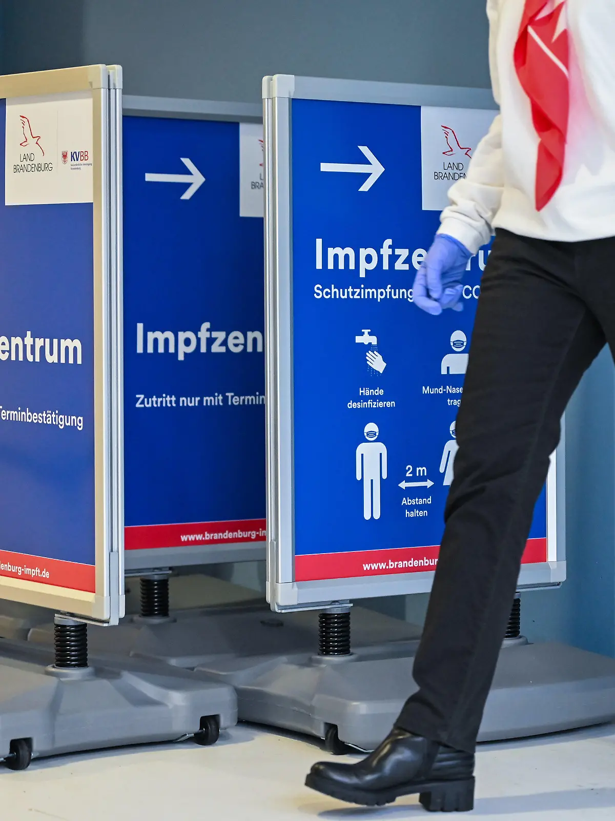 27.01.2021, Brandenburg, Eberswalde: Mehrere Wegweiser zum Impfzentrum Eberswalde stehen in einem Raum. Bis Anfang Februar sollen landesweit in Brandenburg insgesamt elf Impfzentren am Netz sein. Der Zutritt zu einem Impfzentrum ist nur nach einer Terminbestätigung möglich. Im Land Brandenburg werden Termine für die Corona-Schutzimpfung nur telefonisch über die Rufnummer 116117 vergeben. Foto: Patrick Pleul/dpa-Zentralbild/dpa +++ dpa-Bildfunk +++