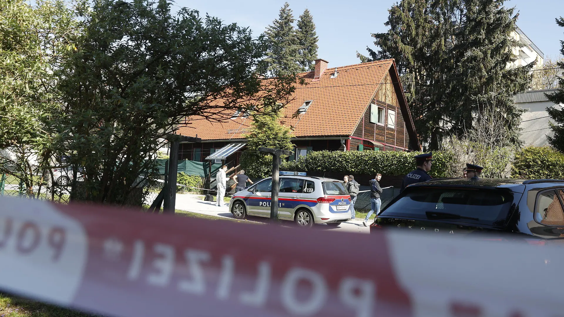 22.04.2023, Österreich, Graz: Polizisten stehen vor dem Wohnhaus, in dem eine Frau getötet worden sein soll. In Graz ist mutmaßlich eine Frau getötet worden und ein unbeteiligter Autofahrer ums Leben gekommen. Am Samstagmorgen fand die Polizei eine schwer verletzte, blutüberströmte Frau in ihrer Wohnung. Laut der Polizei floh ein 28-jähriger Verdächtiger, der mit der Frau mutmaßlich eine Beziehung hatte, mit einem Auto vom Tatort. Nur wenige hundert Meter weiter krachte er frontal in ein anderes Fahrzeug. Dessen Lenker starb bei dem Unfall. (zu dpa Österreich: Tödlicher Unfall auf der Flucht nach Tod einer Frau) Foto: Erwin Scheriau/APA/dpa +++ dpa-Bildfunk +++