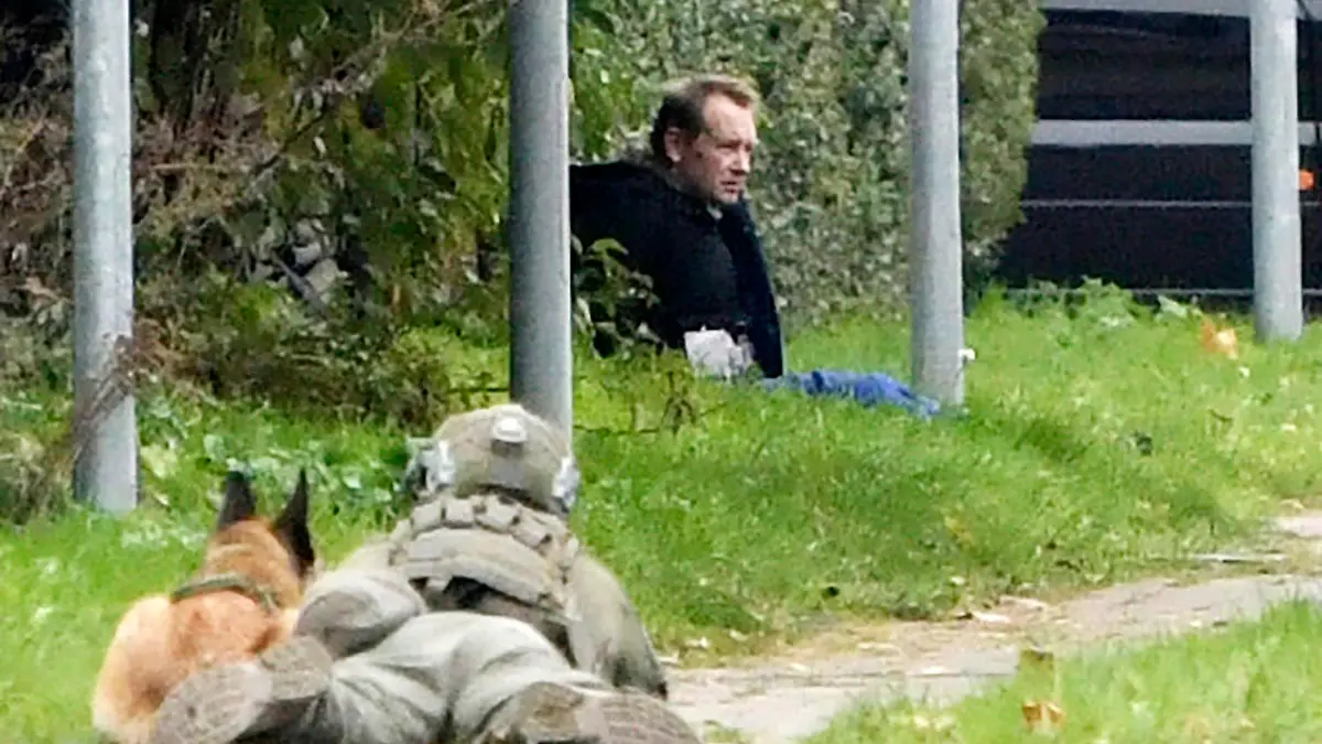 SCREENSHOT - 20.10.2020, Dänemark, Albertslund: Ein Polizist (l) liegt neben einem Polizeihund am Boden und beobachtet Peter Madsen, dänischer Erfinder und verurteilter Mörder, der nach einem gescheiterten Fluchtversuch an einem Straßenrand auf dem Boden sitzt (bestmögliche Qualität). Madsen, der vor drei Jahren für die Tötung der schwedischen Journalistin Wall zu lebenslanger Haft verurteilt worden war, hatte versucht, aus einem Gefängnis in der Kopenhagener Vorstadt fliehen. Foto: Nils Meilvang/Ritzau Scanpix/AP/dpa +++ dpa-Bildfunk +++