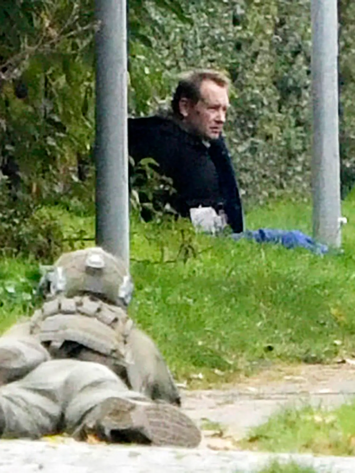 SCREENSHOT - 20.10.2020, Dänemark, Albertslund: Ein Polizist (l) liegt neben einem Polizeihund am Boden und beobachtet Peter Madsen, dänischer Erfinder und verurteilter Mörder, der nach einem gescheiterten Fluchtversuch an einem Straßenrand auf dem Boden sitzt (bestmögliche Qualität). Madsen, der vor drei Jahren für die Tötung der schwedischen Journalistin Wall zu lebenslanger Haft verurteilt worden war, hatte versucht, aus einem Gefängnis in der Kopenhagener Vorstadt fliehen. Foto: Nils Meilvang/Ritzau Scanpix/AP/dpa +++ dpa-Bildfunk +++
