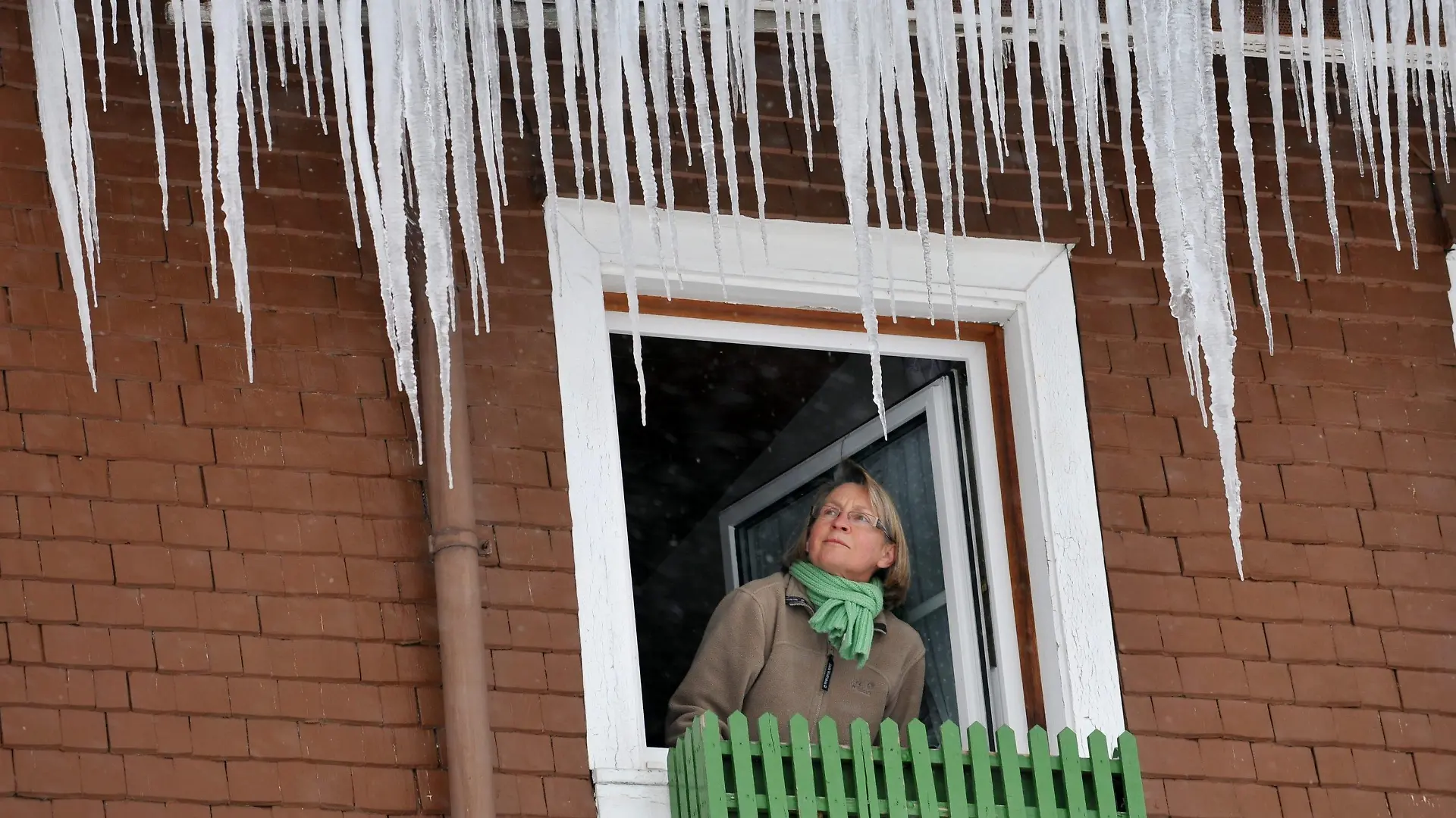Lange Eiszapfen hängen am Mittwoch (13.01.2010) von der Dachrinne des Schwarzwälder Gasthofs "Löwen" in Breitnau (Kreis Breisgau-Hochschwarzwald), während die Wirtin Barbara Herrmann aus dem Fenster schaut. Der Winter hat die Hochlagen des Schwarzwalds weiter fest im Griff, während nach Vorhersage der Meteorologen in den Tallagen die Temperaturen in den nächsten Tagen über null Grad steigen können. Foto: Rolf Haid dpa/lsw +++(c) dpa - Bildfunk+++
